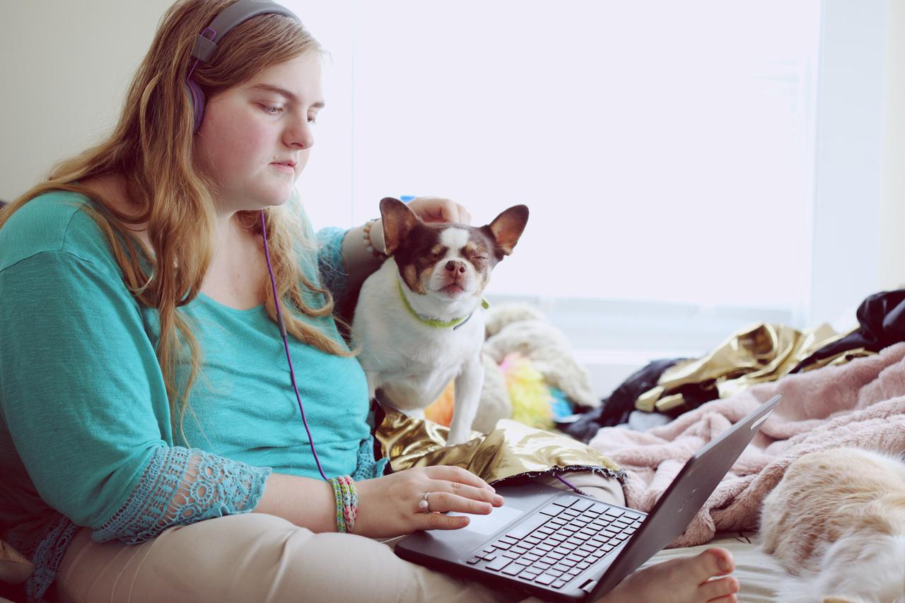 A 19-year-old woman with Autism and other learning disabilities using her laptop at home for school. 
