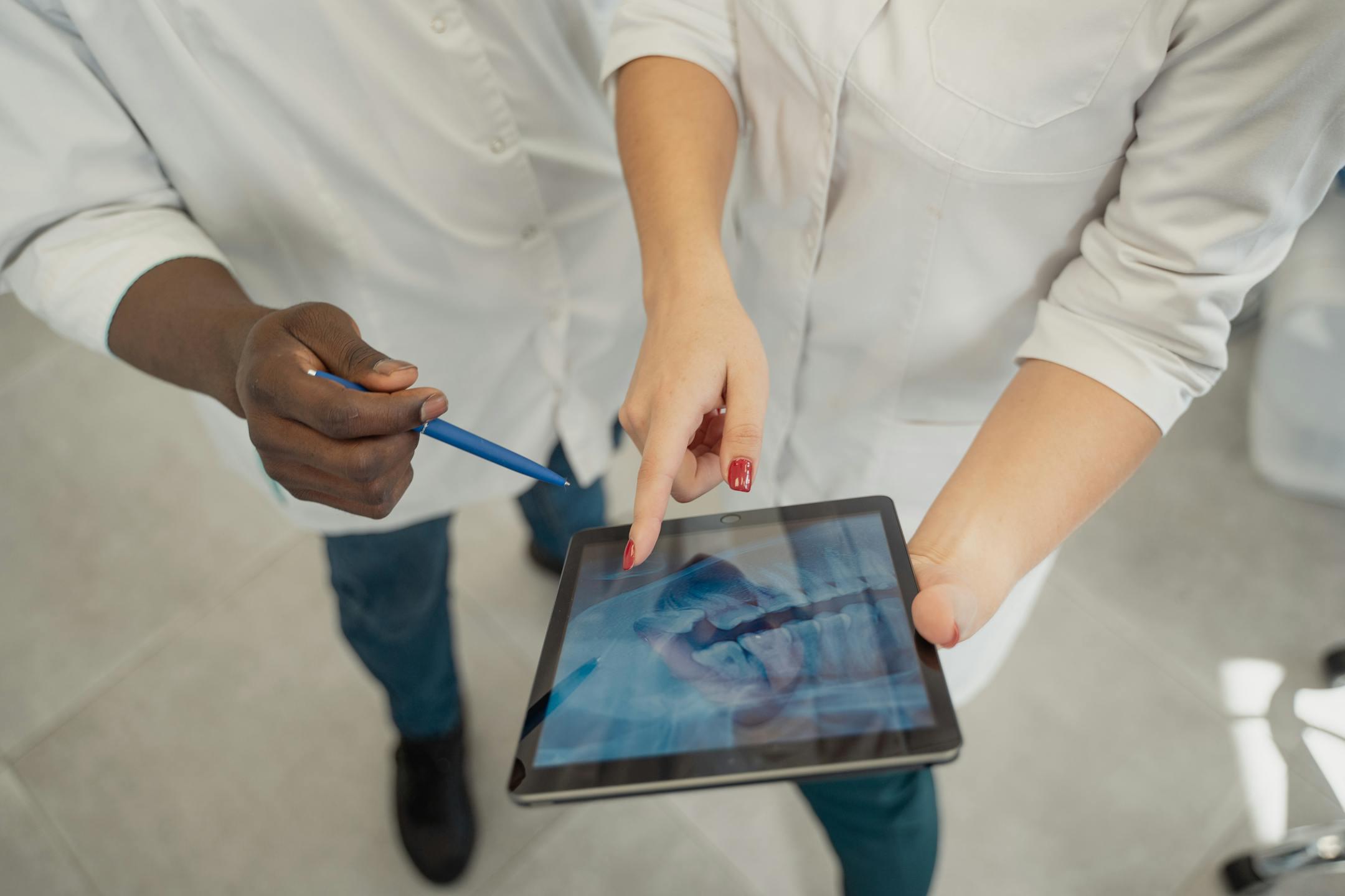 Two medical professionals analyzing a dental x-ray on a tablet. Collaborative healthcare setting.