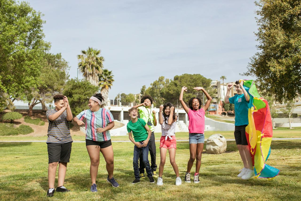 A group of happy children having fun flying a kite in a sunny park, enjoying friendship outdoors.