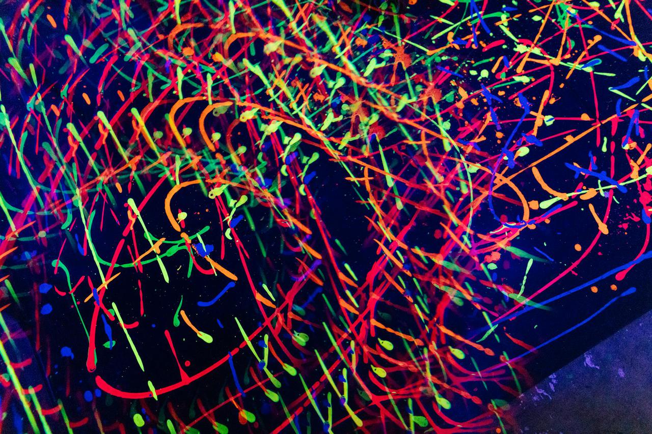 Dynamic neon abstract artwork featuring glowing patterns and vibrant colors under UV light.