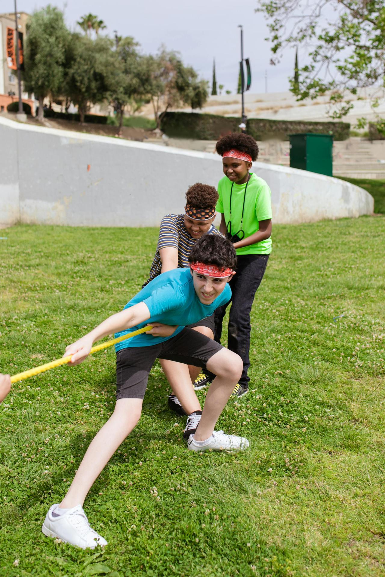 Group of children enjoying a tug of war game outdoors on a grassy field.