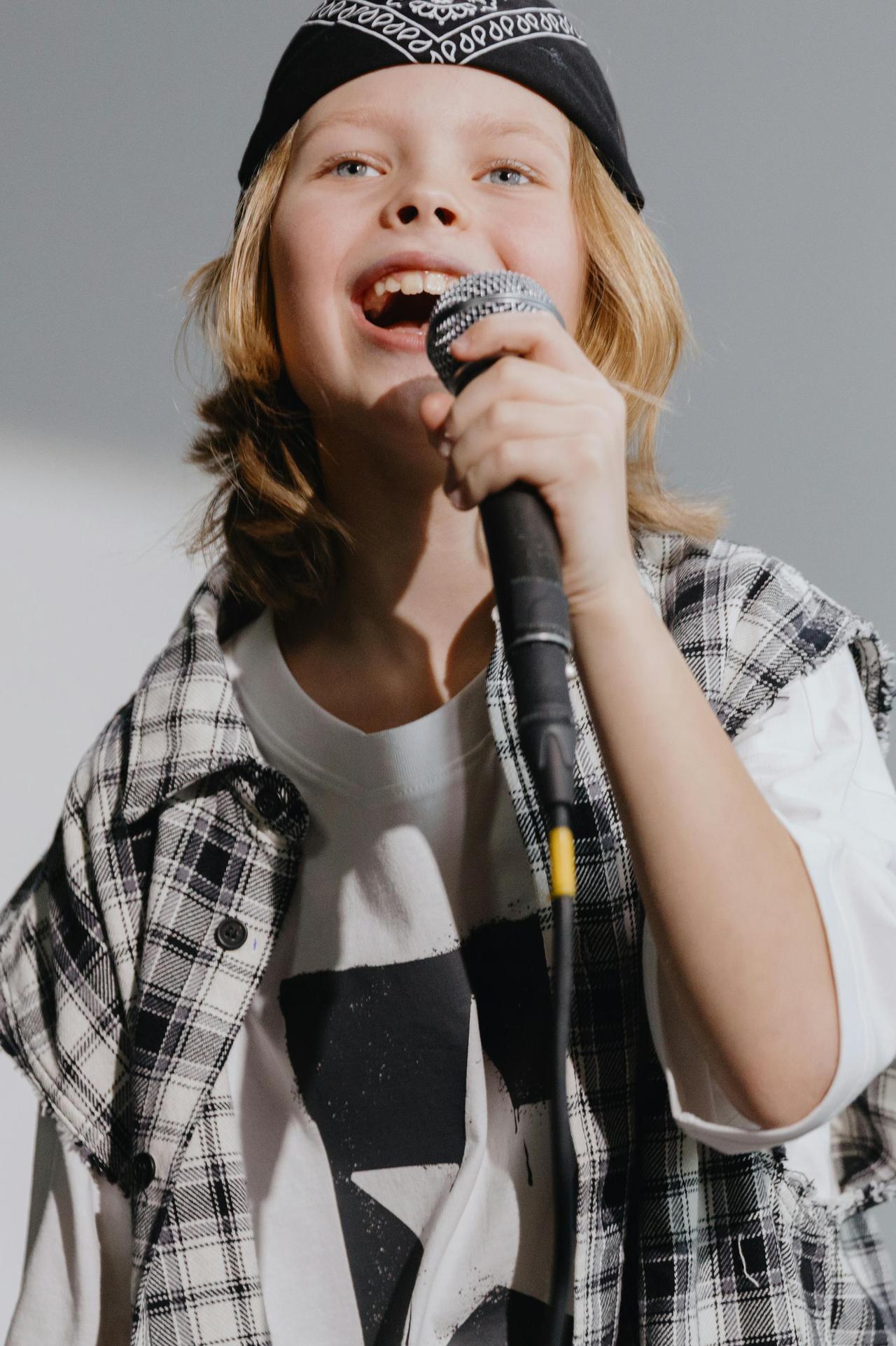 Joyful young girl in bandana passionately singing into a microphone.