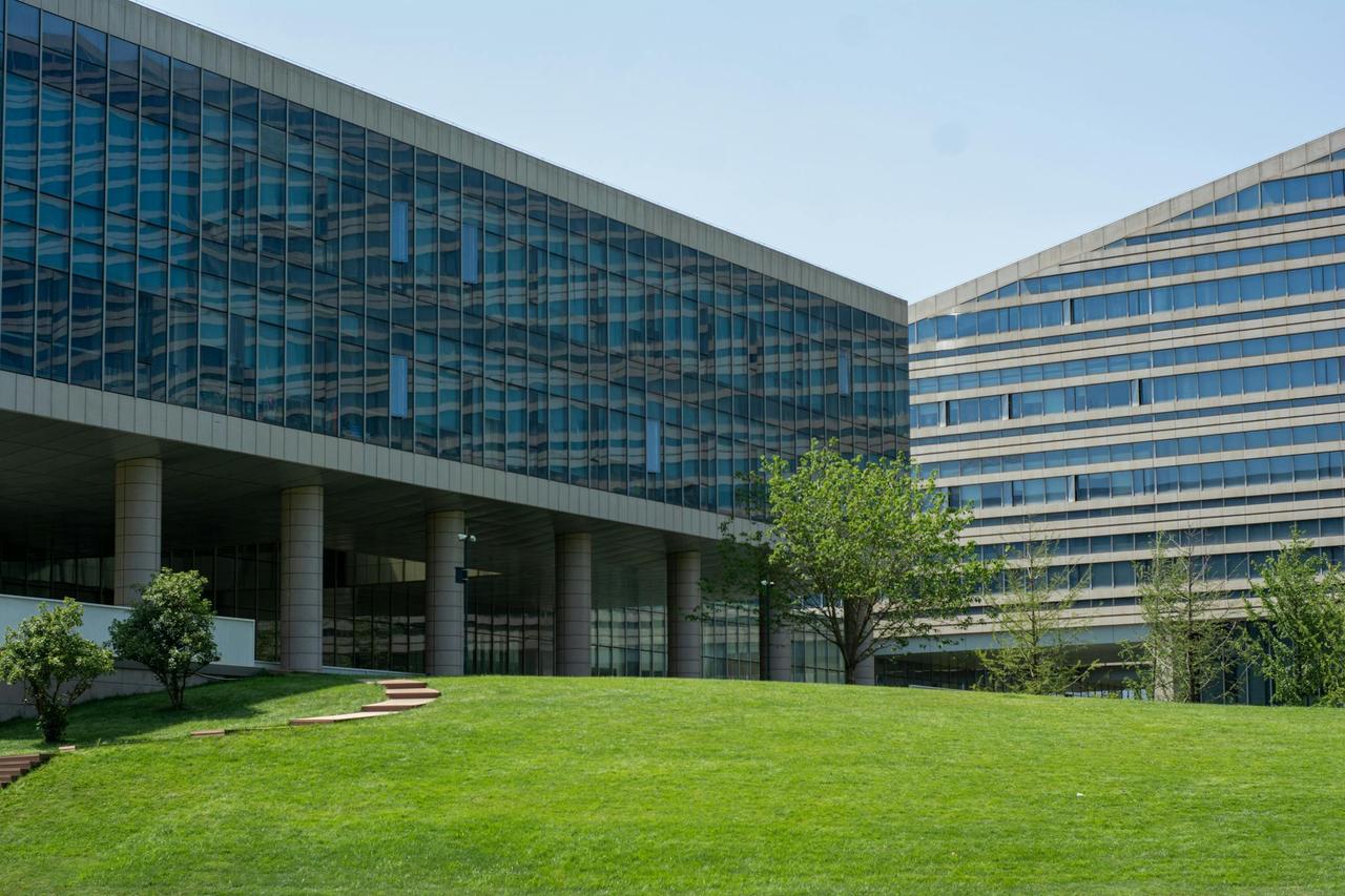 Contemporary glass office building surrounded by lush green grass in daylight.