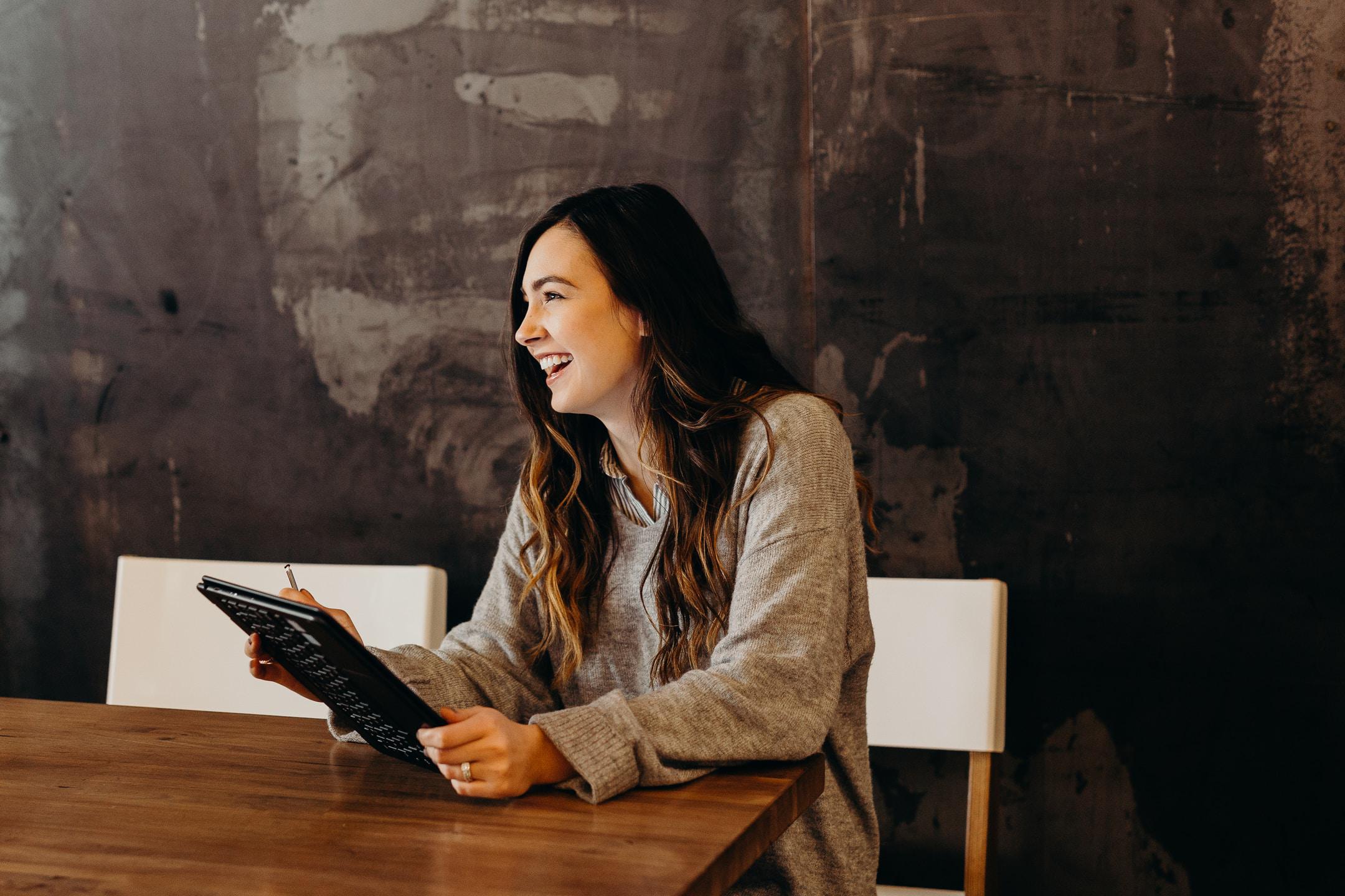 Image of a woman holding a tablet and laughing because she met with a career planning coach.