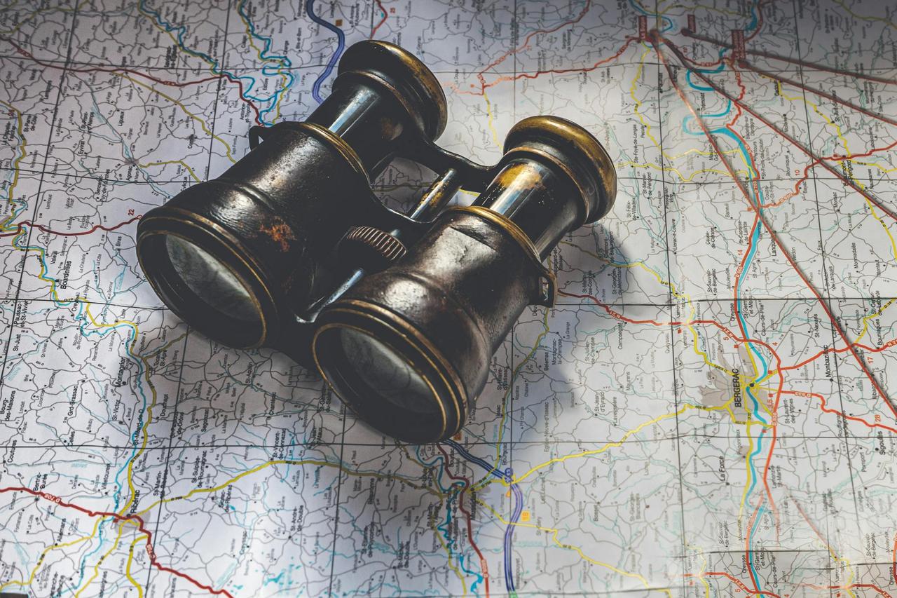 Close-up of antique binoculars placed on a detailed map, evoking adventure.