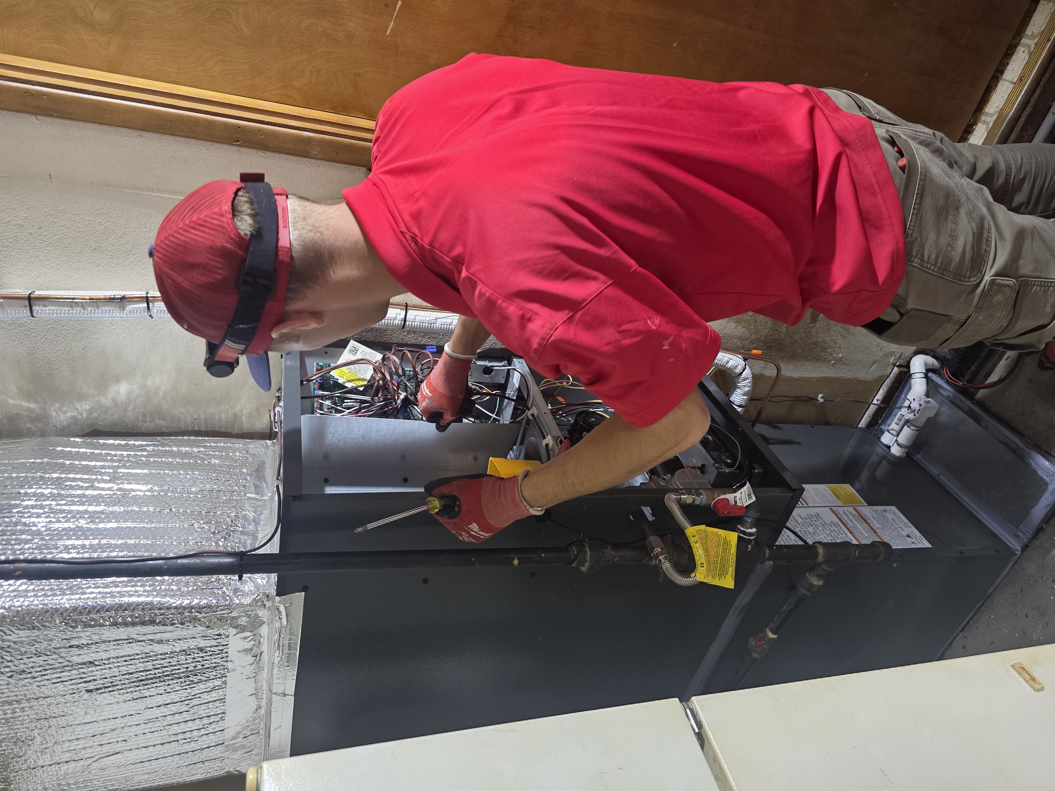 Technician in red shirt working on HVAC system
