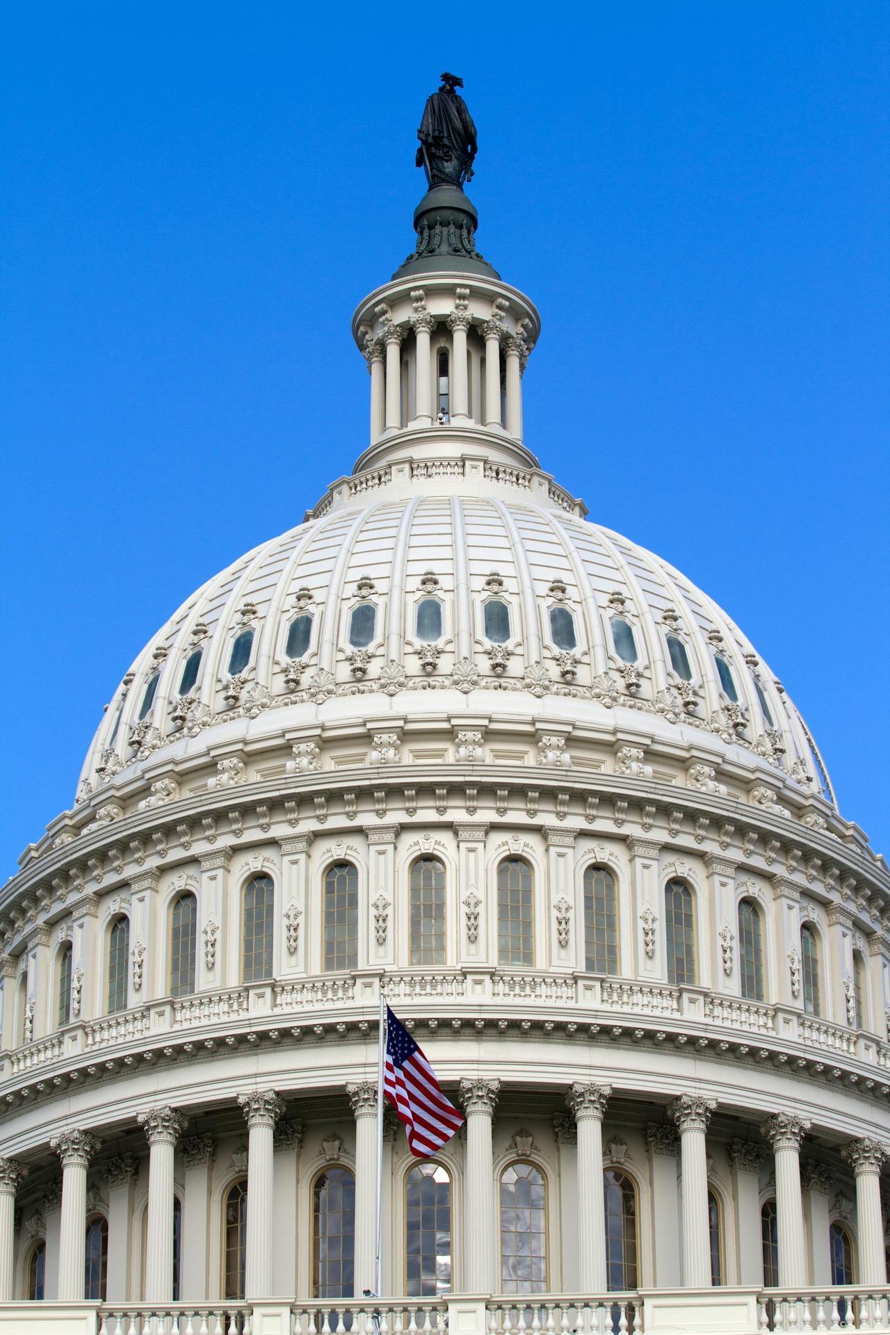 Close-up of the iconic dome of the United States Capitol building in Washington, DC against a clear blue sky.