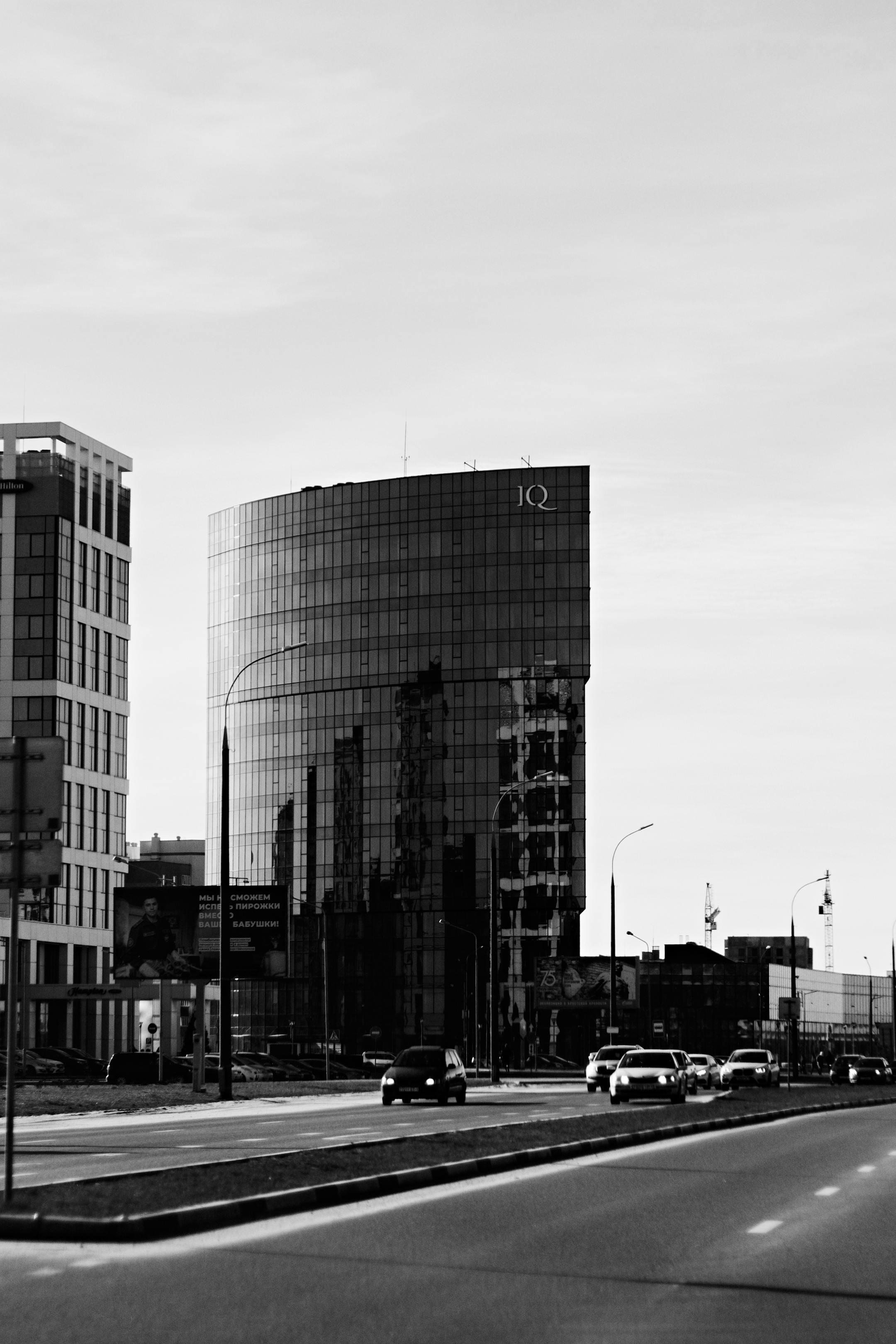 Black and white photograph of a modern skyscraper in an urban city setting, reflecting contemporary architecture.