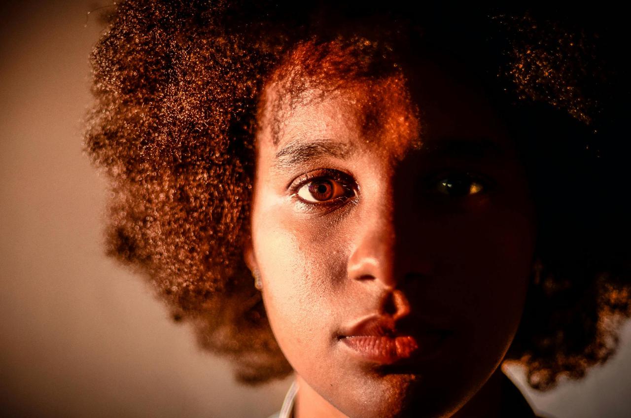 A captivating close-up portrait of a woman with dramatic lighting emphasizing half her face.