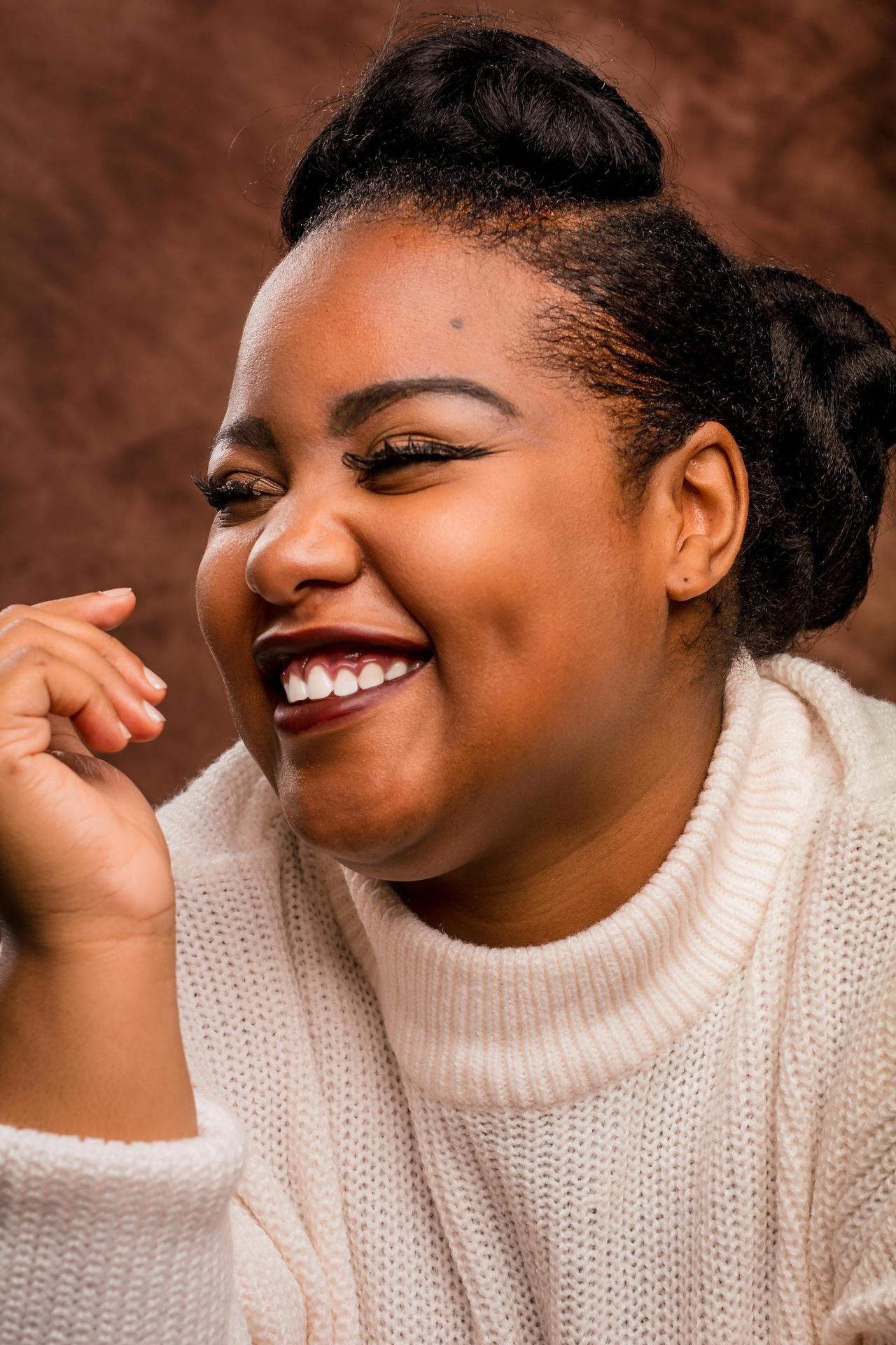 Close-up of a joyful African American woman with elegant hairstyle smiling in a studio setting.