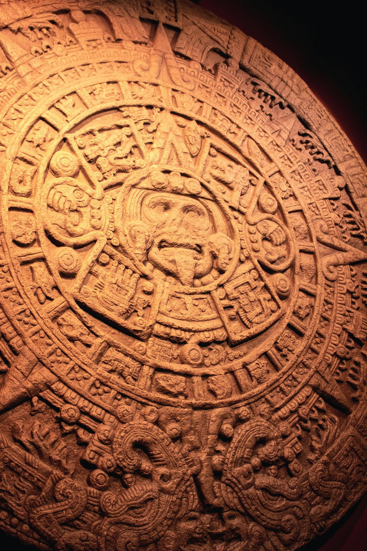 Detailed view of an intricately carved ancient Mayan calendar stone displaying symbols and patterns.