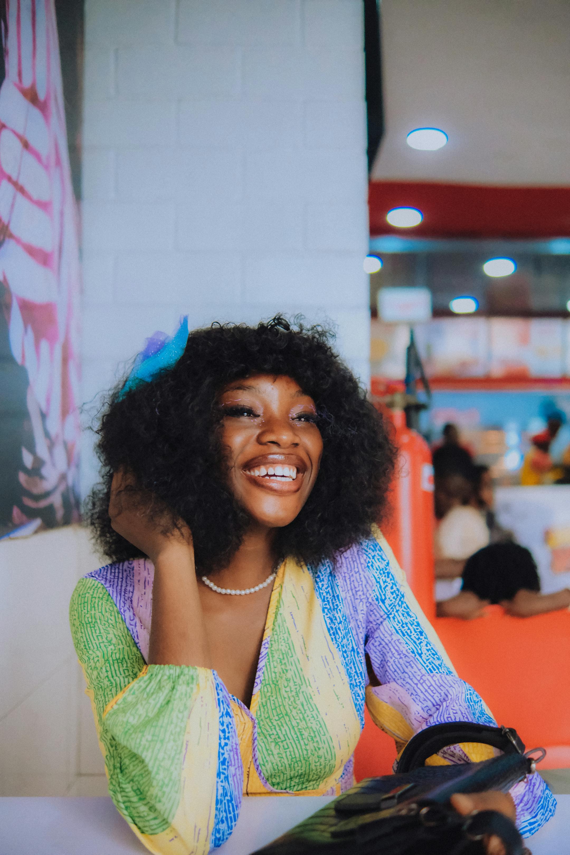 Smiling woman with colorful outfit in a lively restaurant interior.