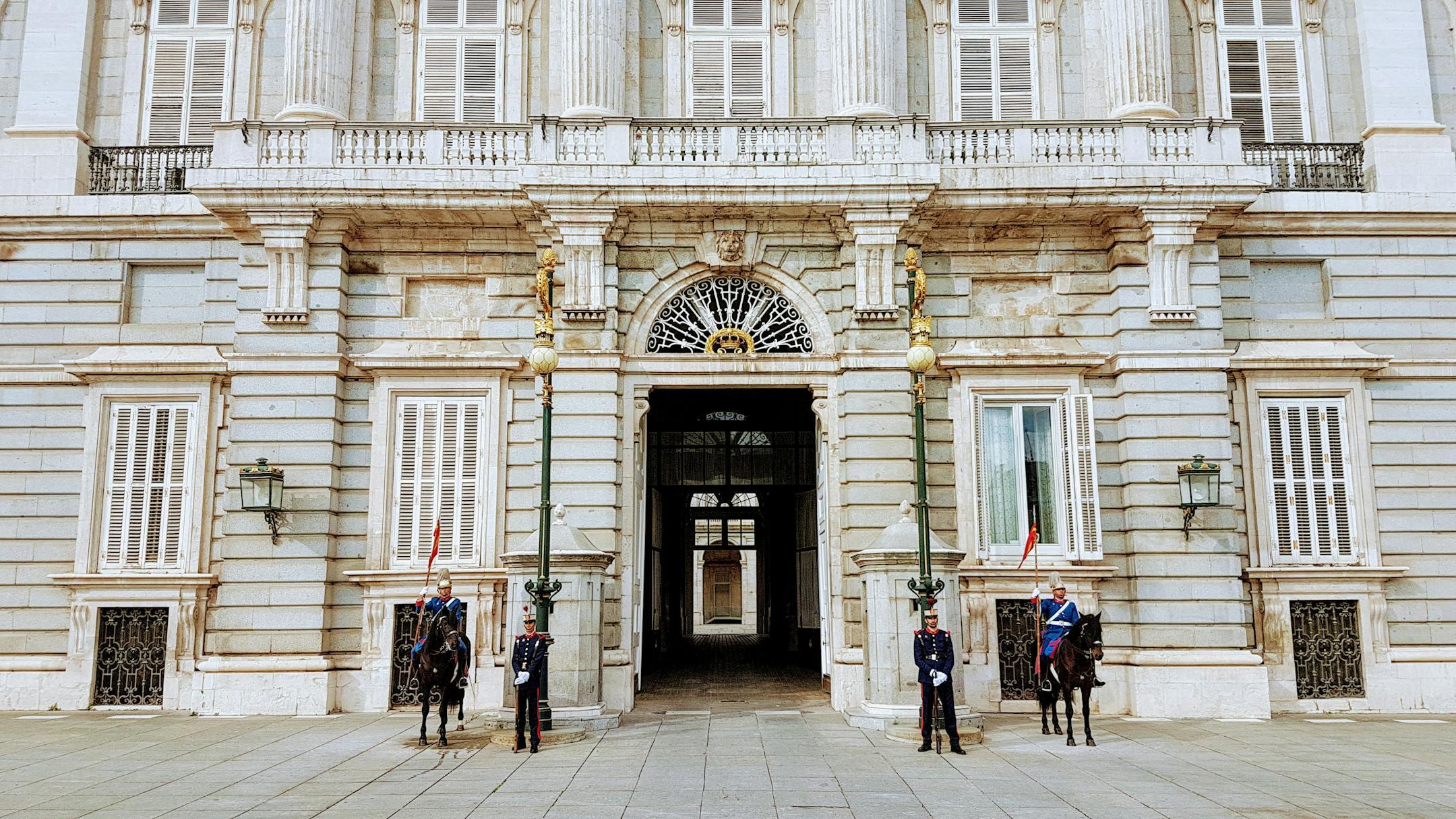 Guards and cavalry stand at the Royal Palace of Madrid entrance, showcasing Spanish heritage.