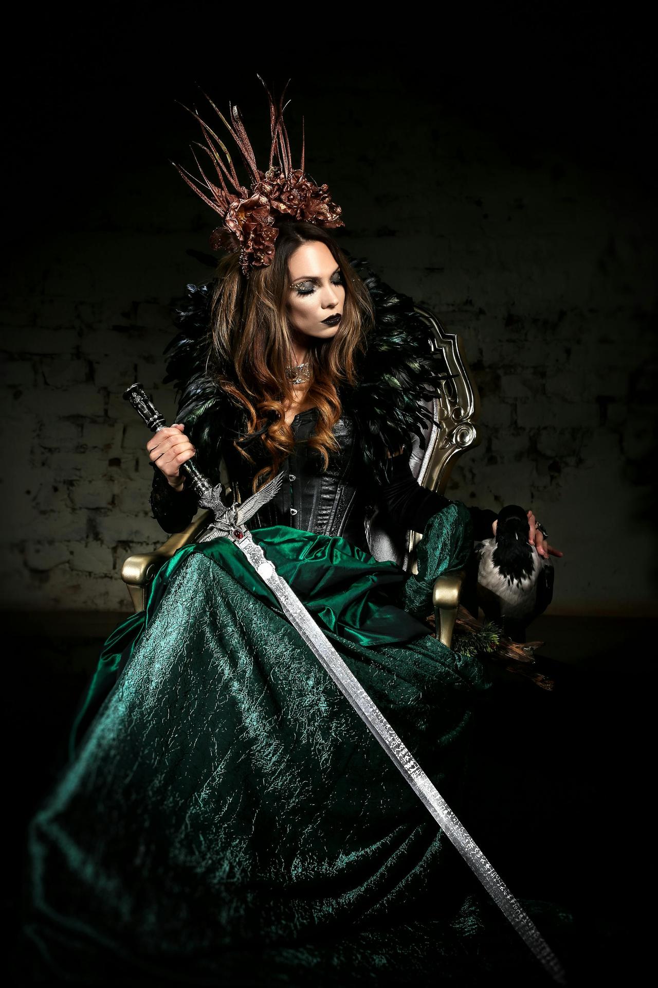 A dramatic and enchanting portrait of a woman in a fantasy witch costume holding a sword.