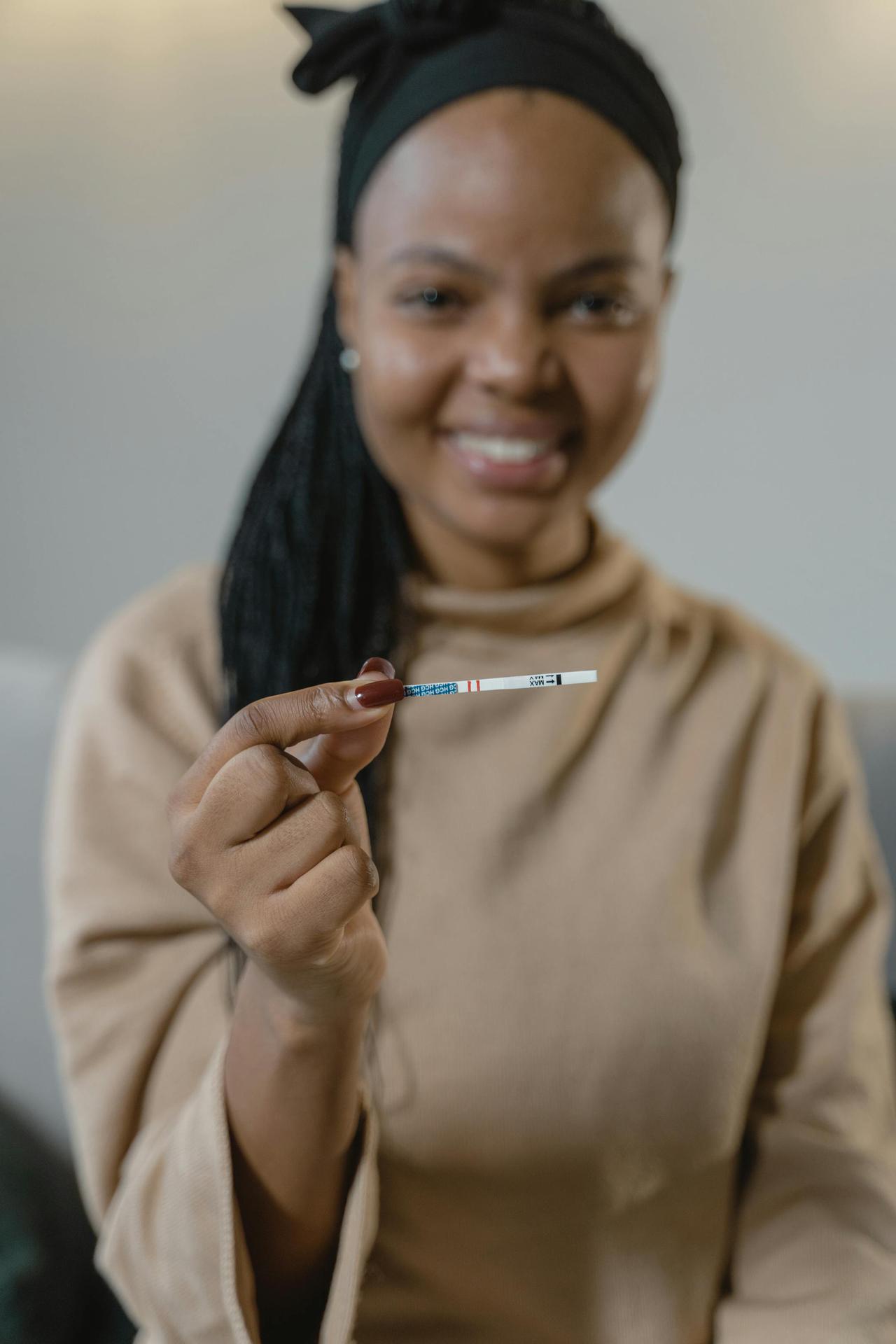 A joyful woman shows a positive pregnancy test, celebrating her pregnancy.