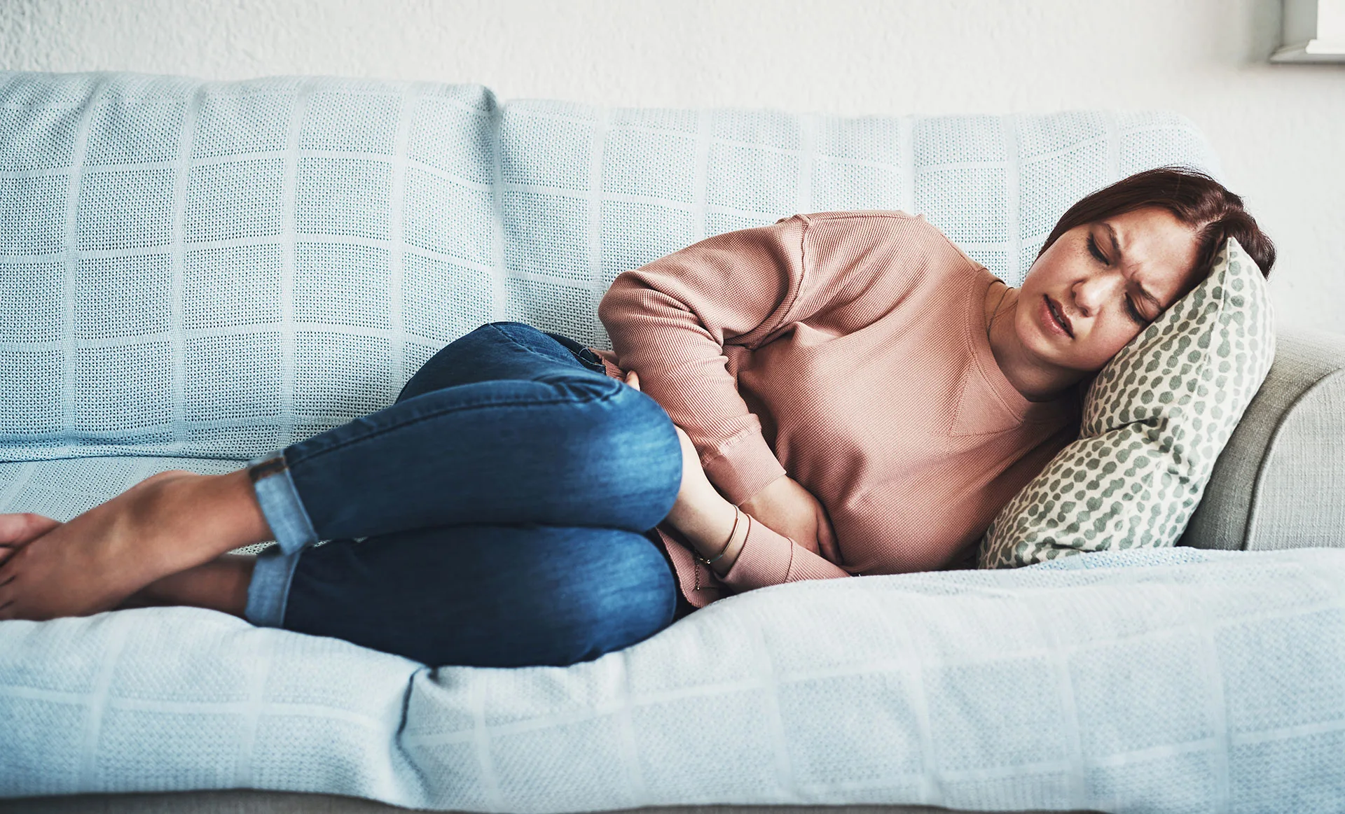 woman-with-pms-belly-cramps-lying-on-couch.webp
