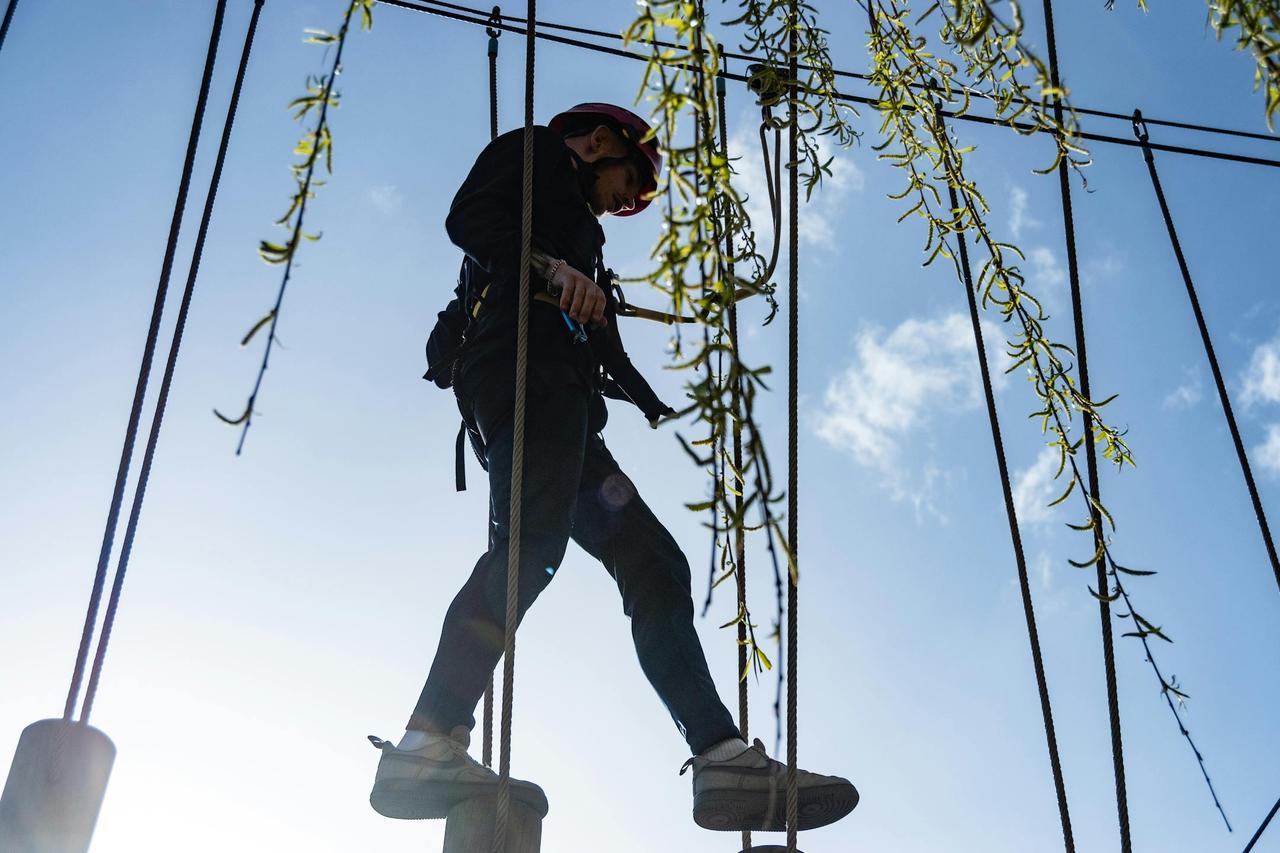 A man wearing safety gear enjoys a high ropes course on a sunny day in Scarborough, UK.