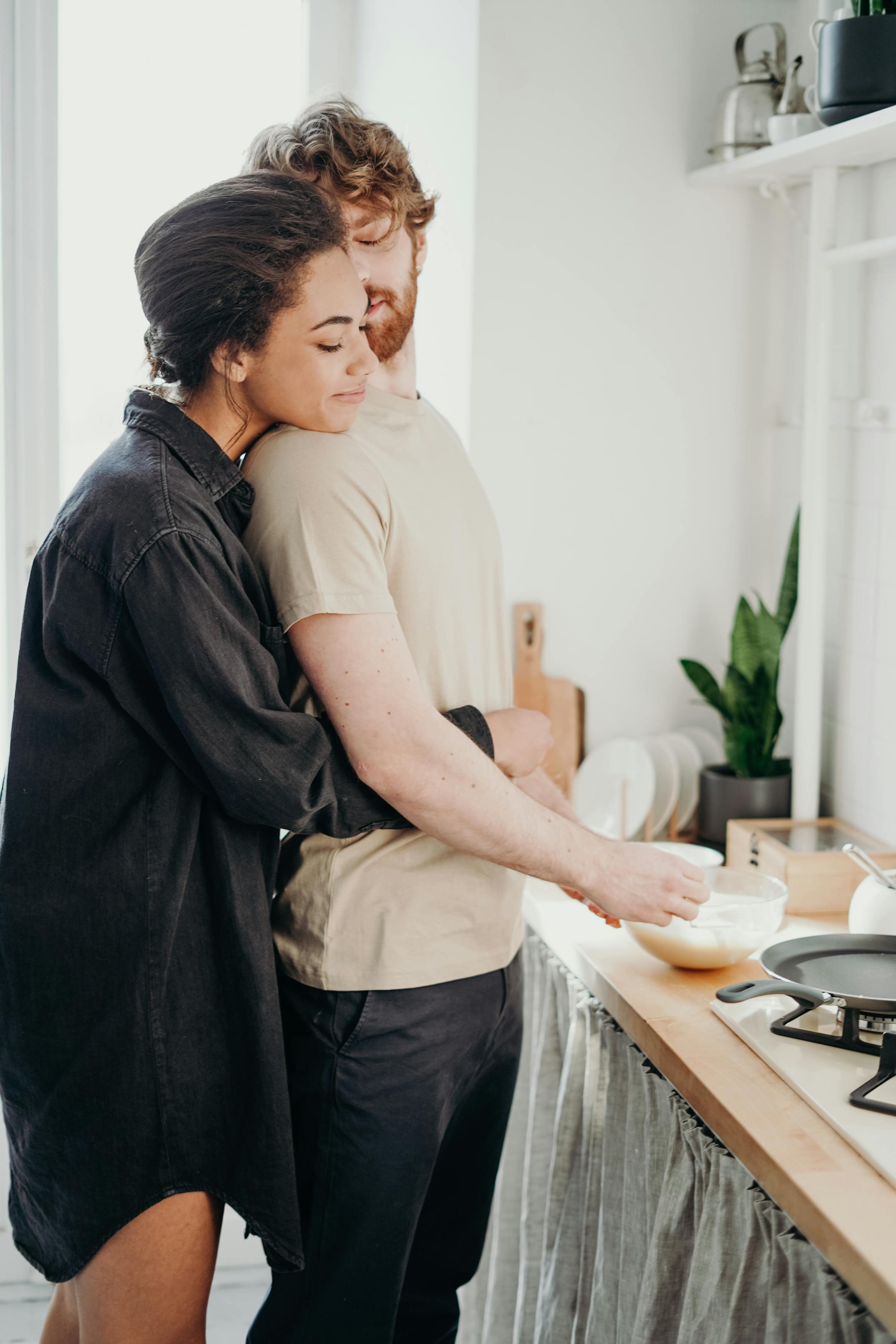 Young couple embracing in a cozy kitchen, smiling as Cognitive Analytica clients starting couples therapy in Lebanon