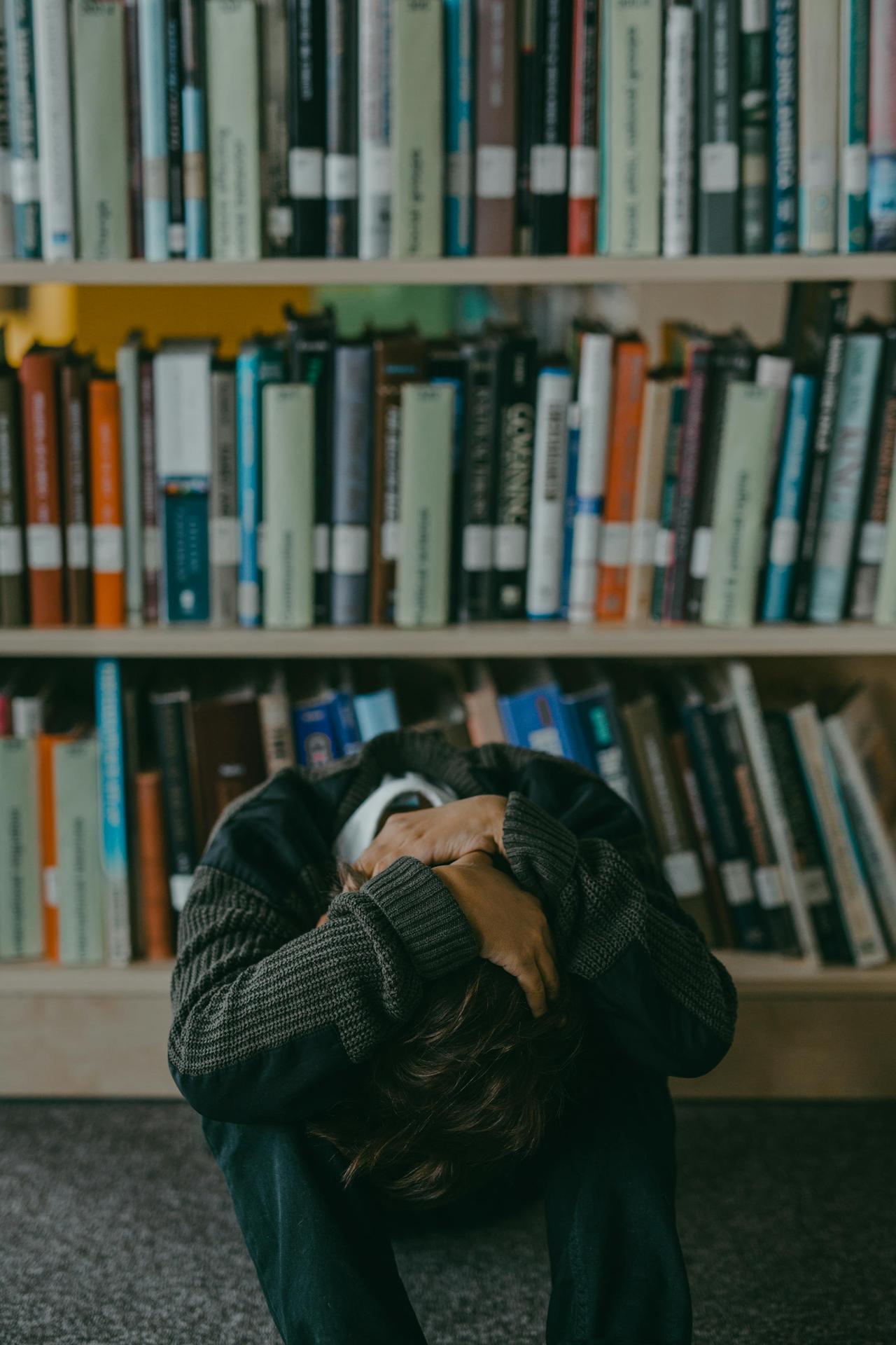 <em>Distressed student sitting on a library floor in Lebanon, symbolizing adolescent depression and the impact of psychotherapy for young people</em>