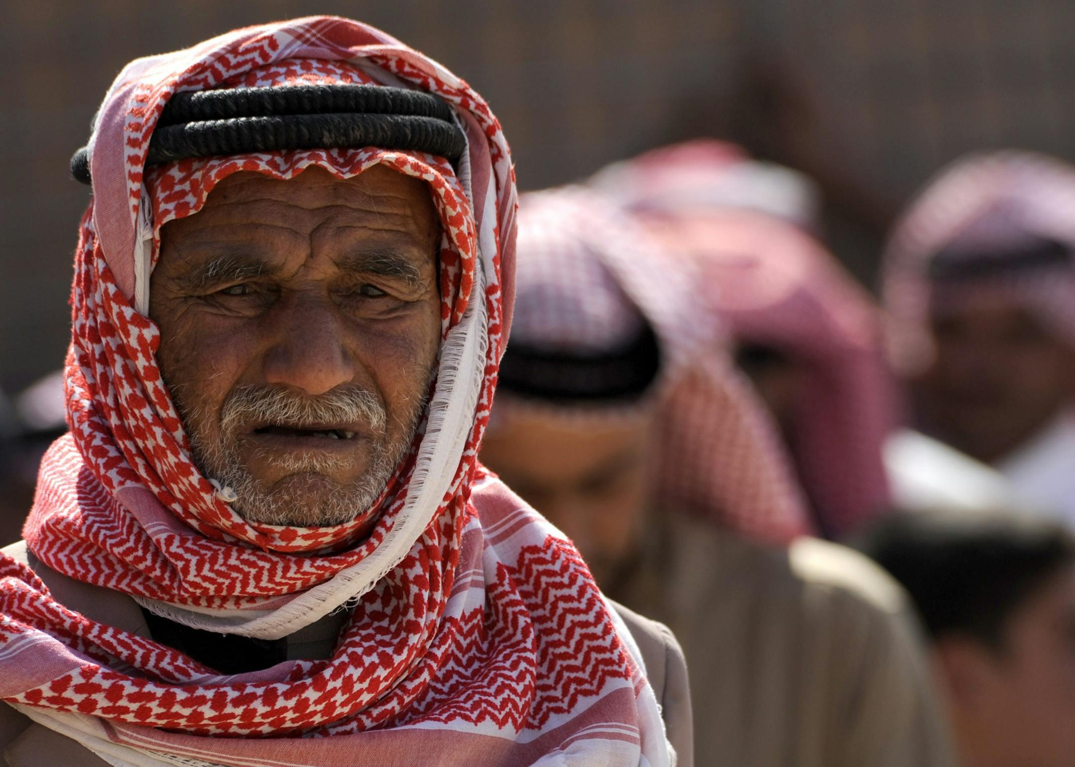 Close-up portrait of an elderly Middle Eastern man wearing a traditional keffiyeh and black agal.
