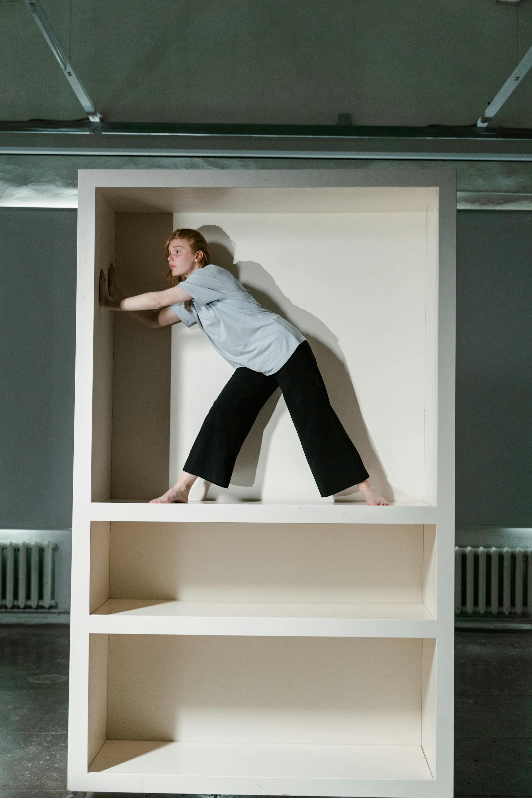 Woman embodying the feeling of claustrophobia within a cabinet, capturing anxiety and stress.