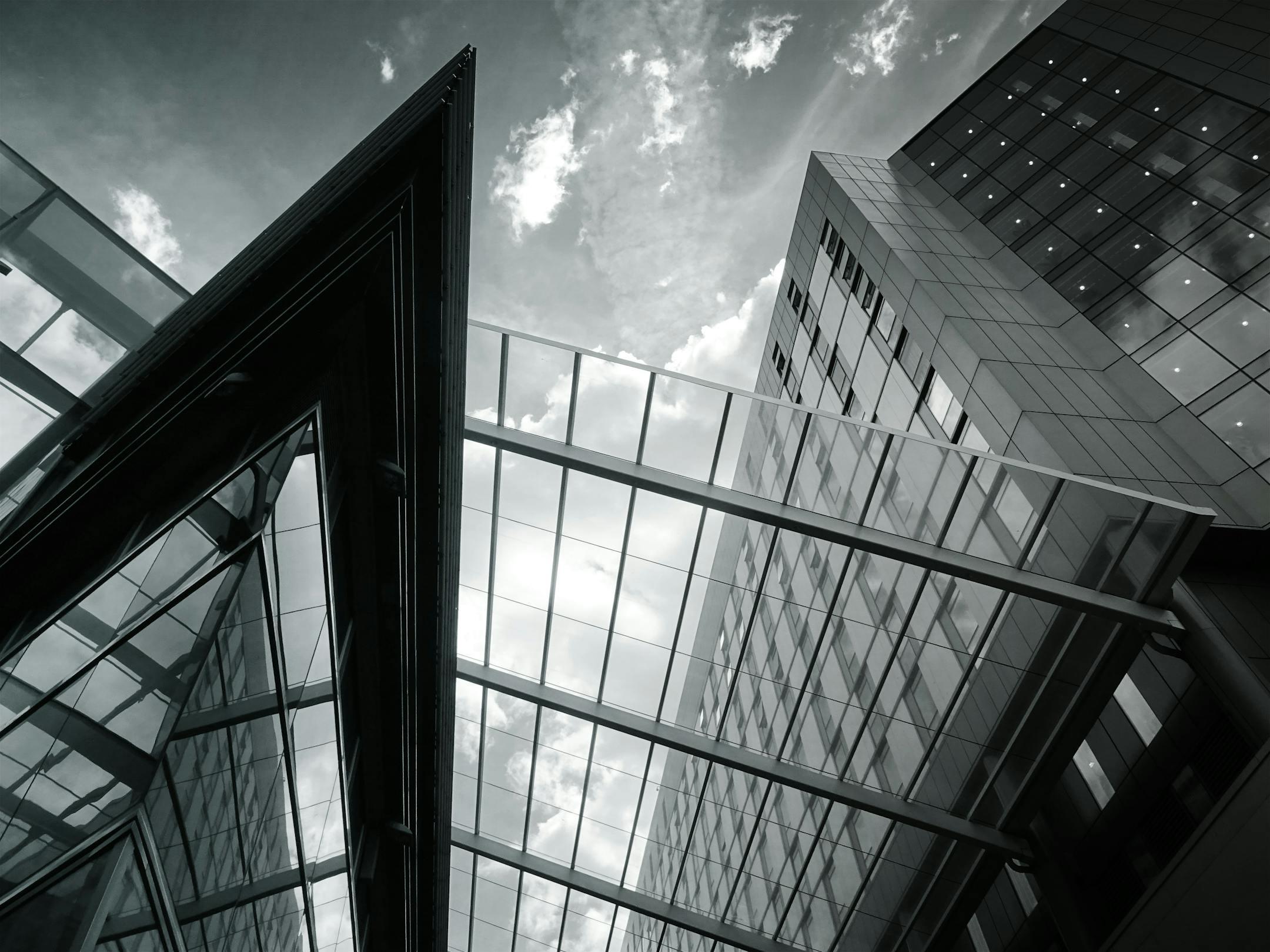 Low angle view of modern glass facade buildings showcasing contemporary architecture with reflections.