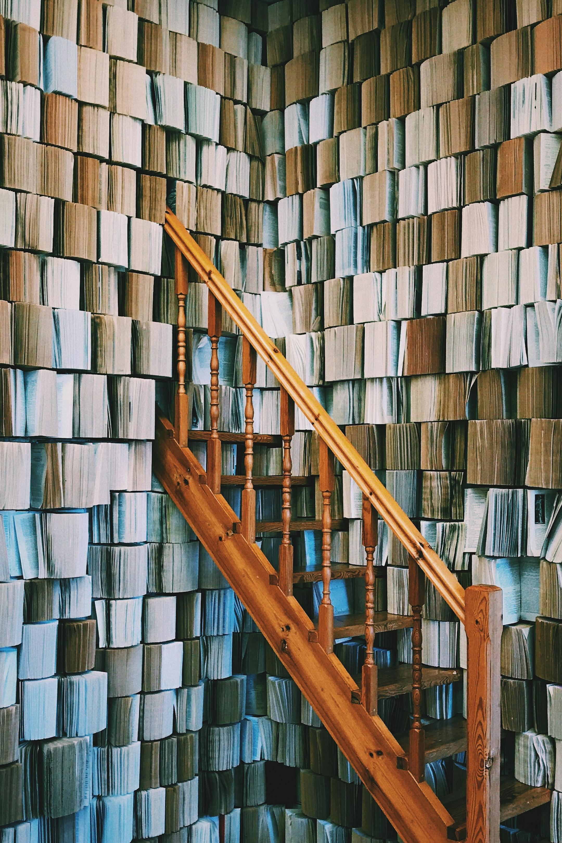 Wooden staircase beside an abstract wall of books, symbolizing Cognitive Analytica’s commitment to continuous psychological learning, exploration, and evidence-based knowledge.