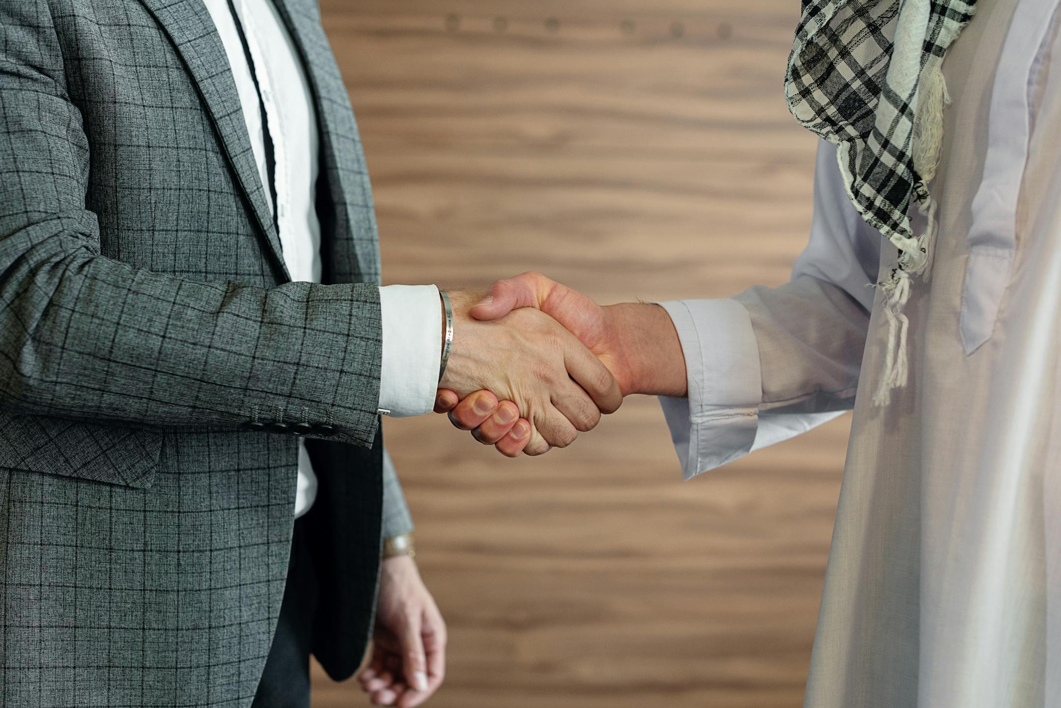 Close-up of a handshake between two men in business attire, symbolizing cooperation and partnership.