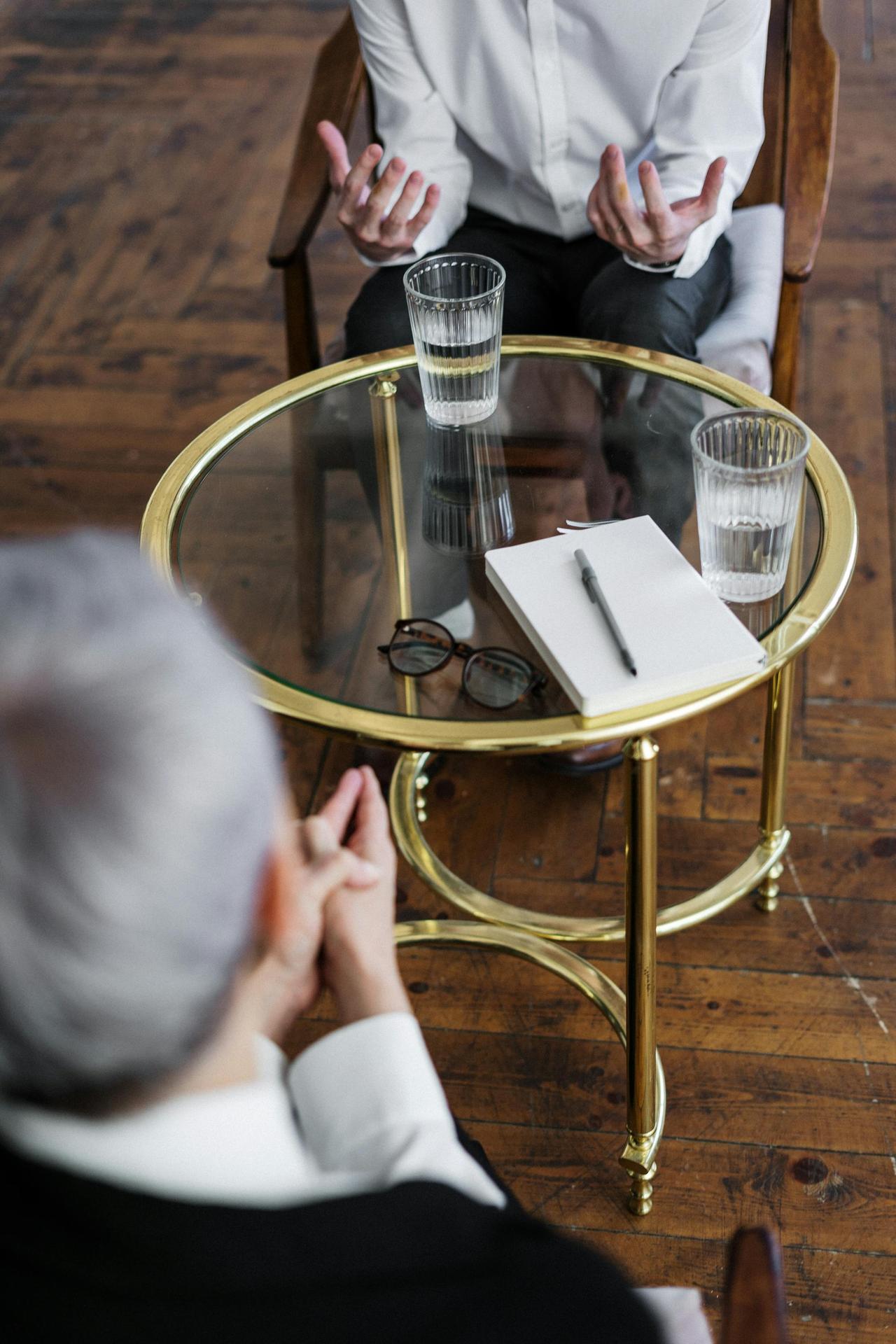 Our Therapist and their patient discussing mental health in a private counseling session at Cognitive Analytica, seated across a glass table in a professional indoor setting