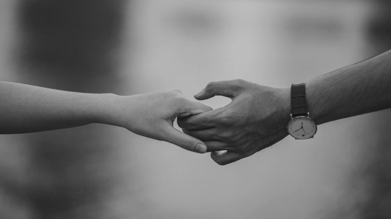 Monochrome image of two hands gently holding, symbolizing emotional connection, trust, and love in couples therapy at Cognitive Analytica