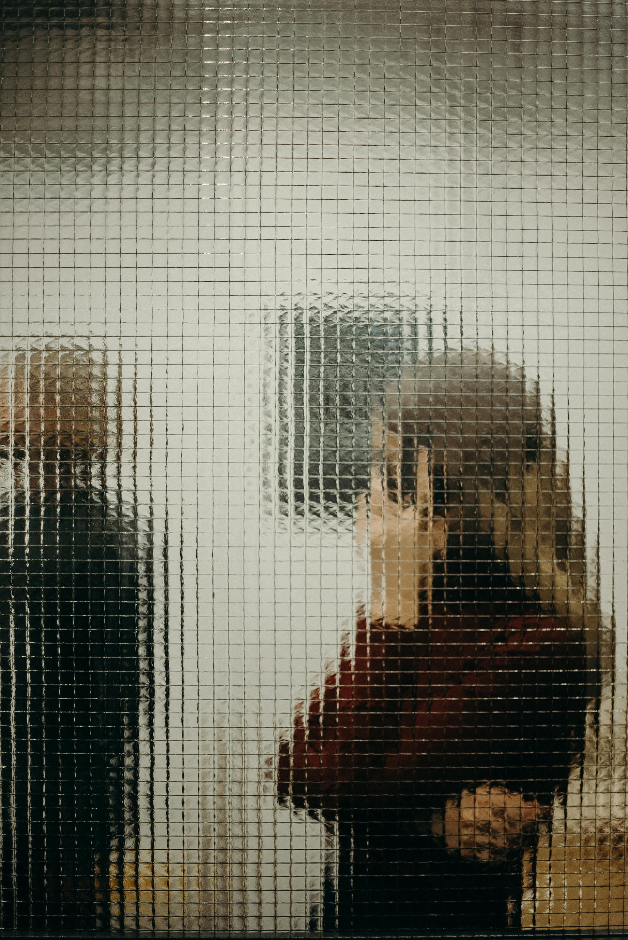 Abstract image of people seen through textured glass, capturing a modern office ambiance.
