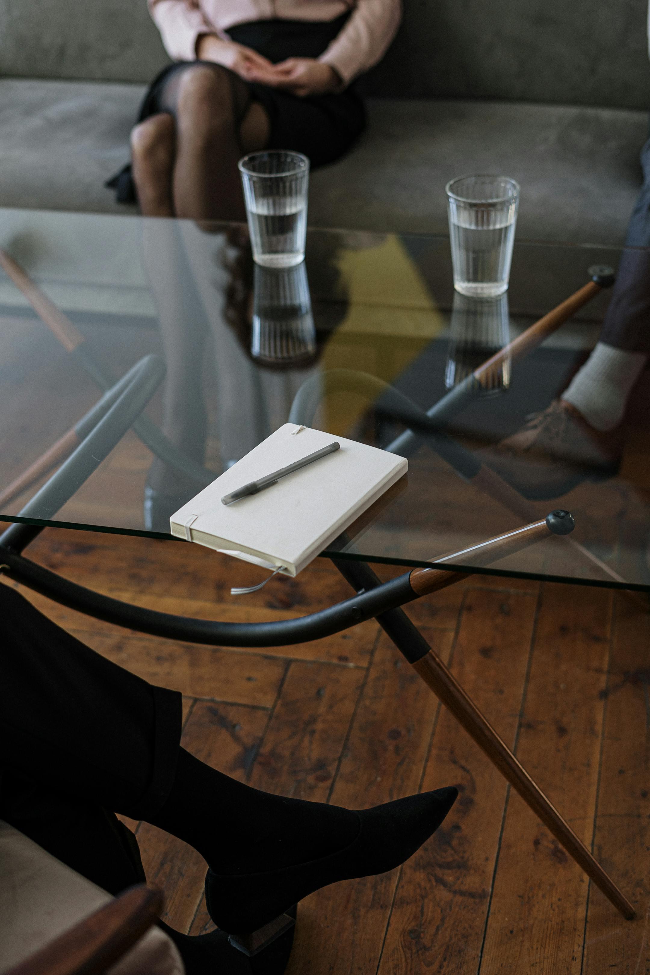 Close-up of a therapy session setup at Cognitive Analytica, featuring two water glasses and a notepad on a glass table during counseling.
