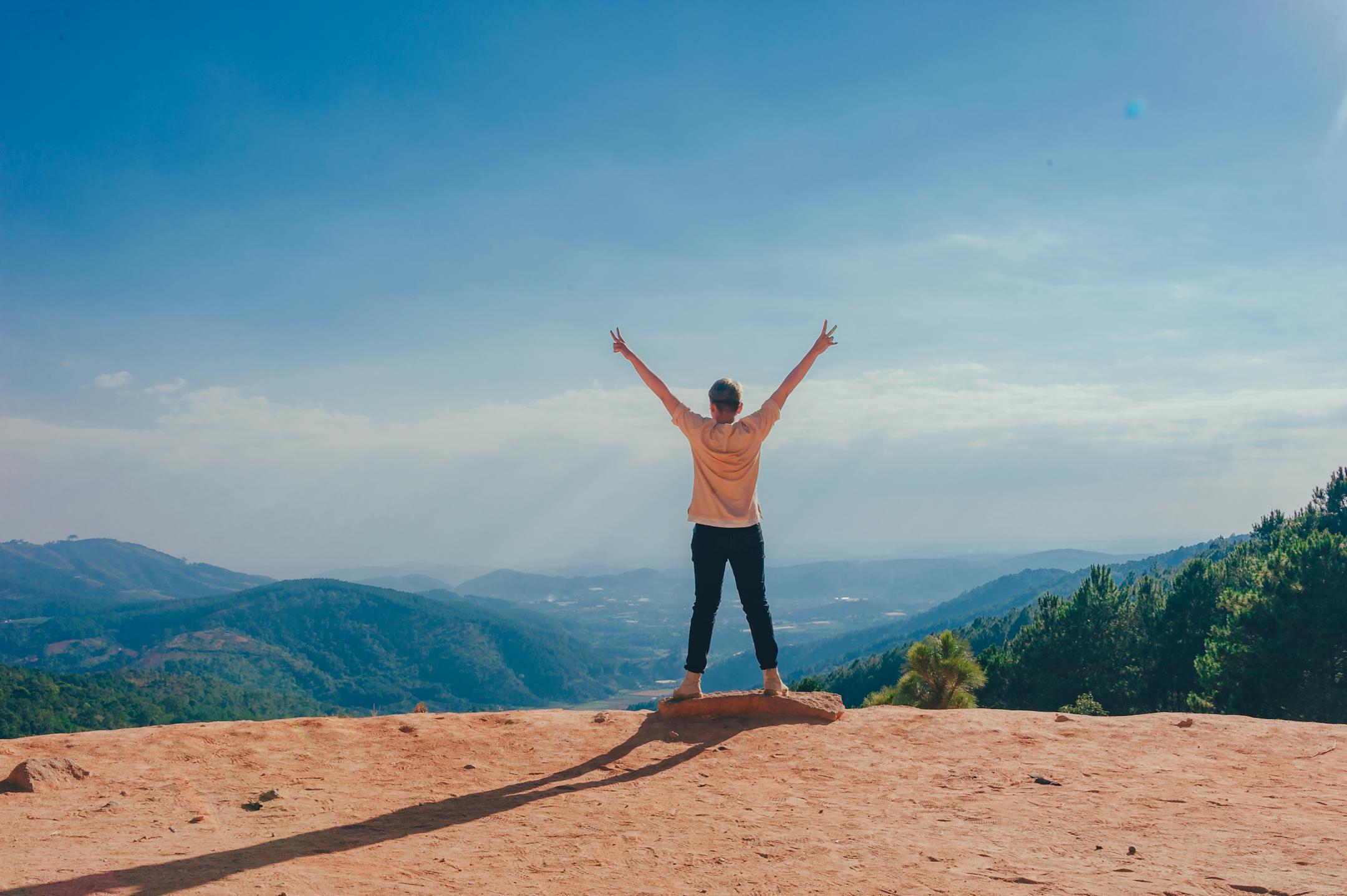 A woman standing victoriously on a mountain top with arms raised, embracing nature and freedom — symbolizing recovery, resilience, and renewed hope — Cognitive Analytica, Lebanon