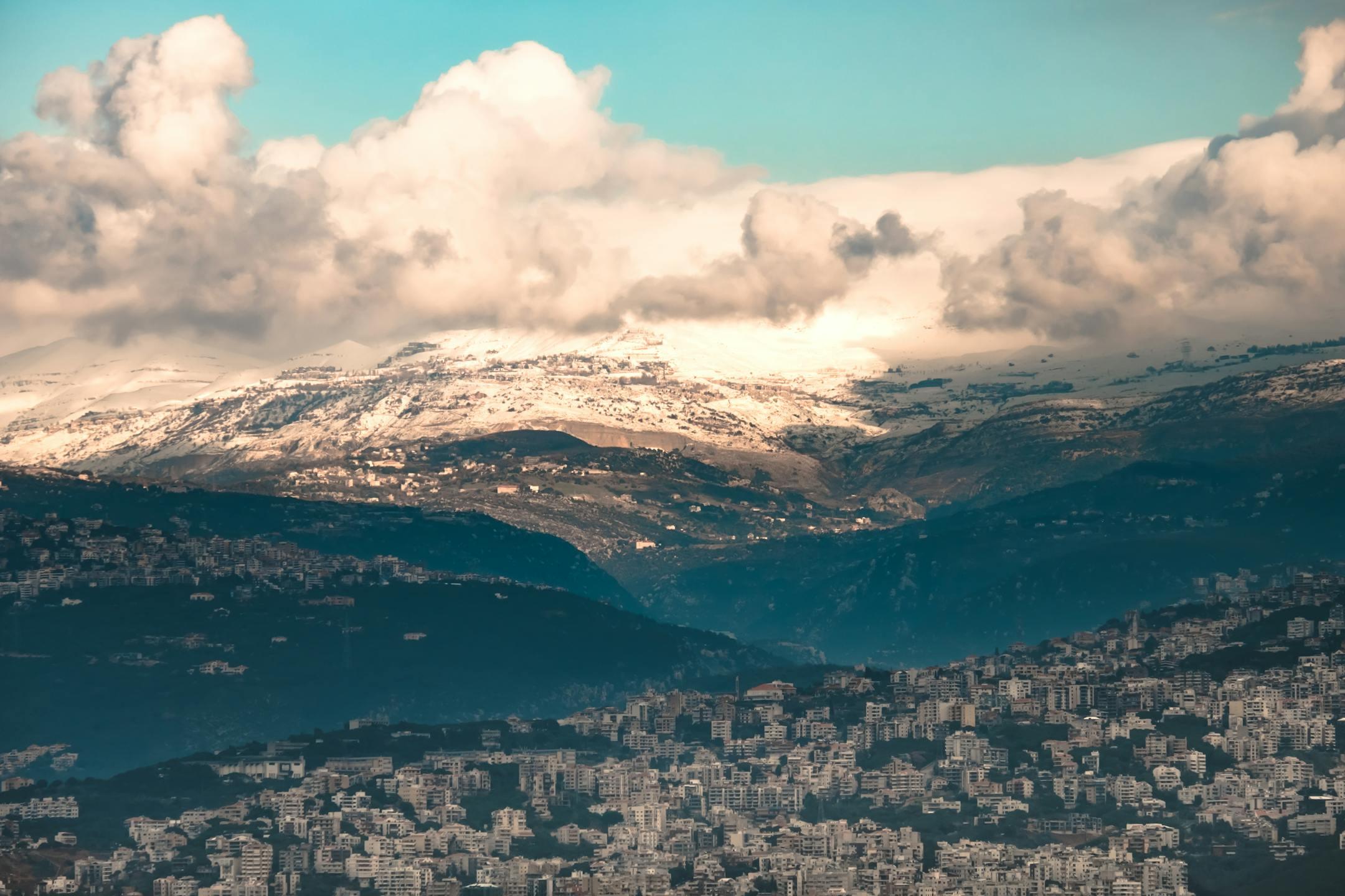 <em>Aerial view of Beirut with snow-capped mountains under a cloudy sky, symbolizing the journey of psychotherapy with Cognitive Analytica in Lebanon</em>