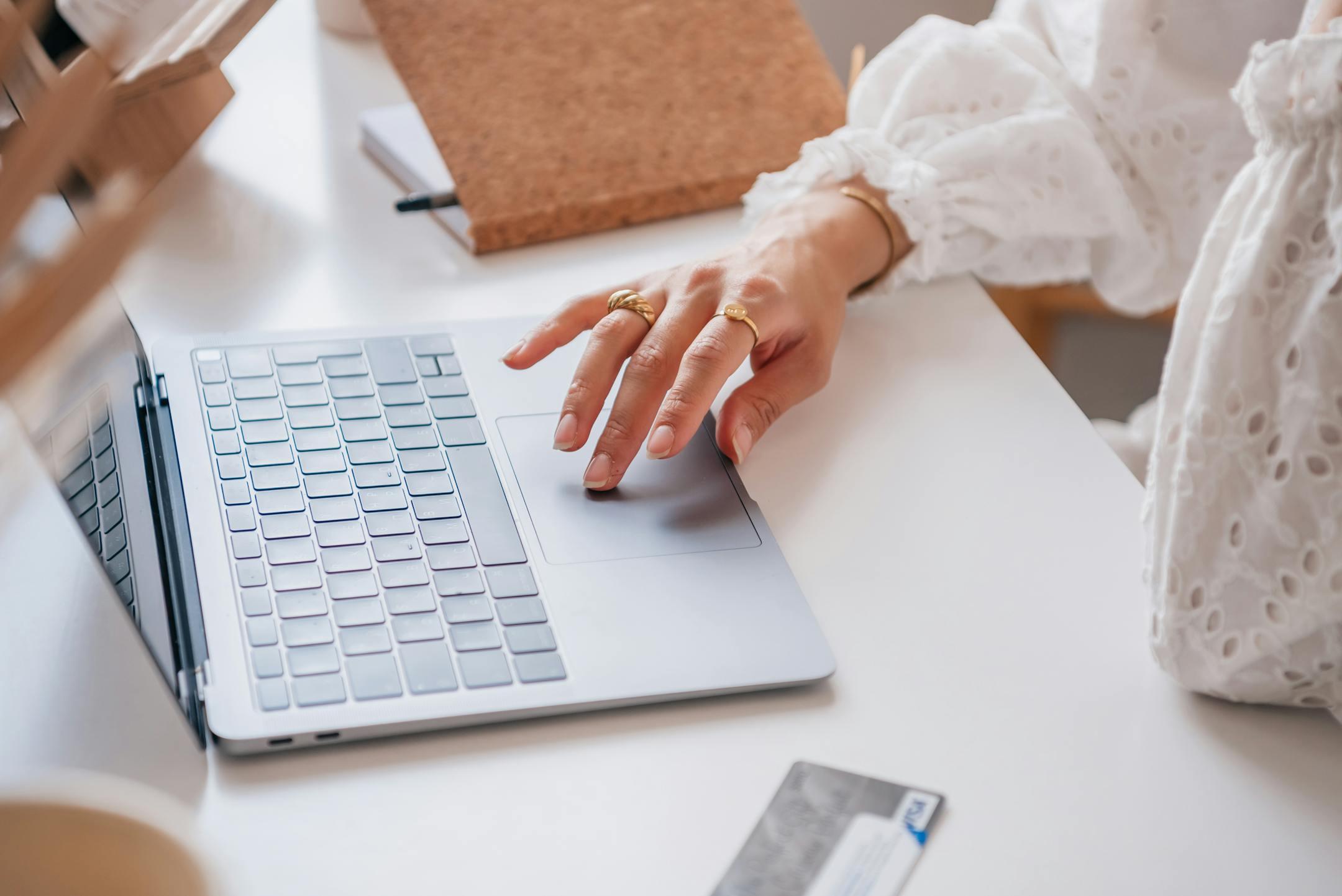 Woman using a laptop for online shopping, showcasing elegant gold rings.