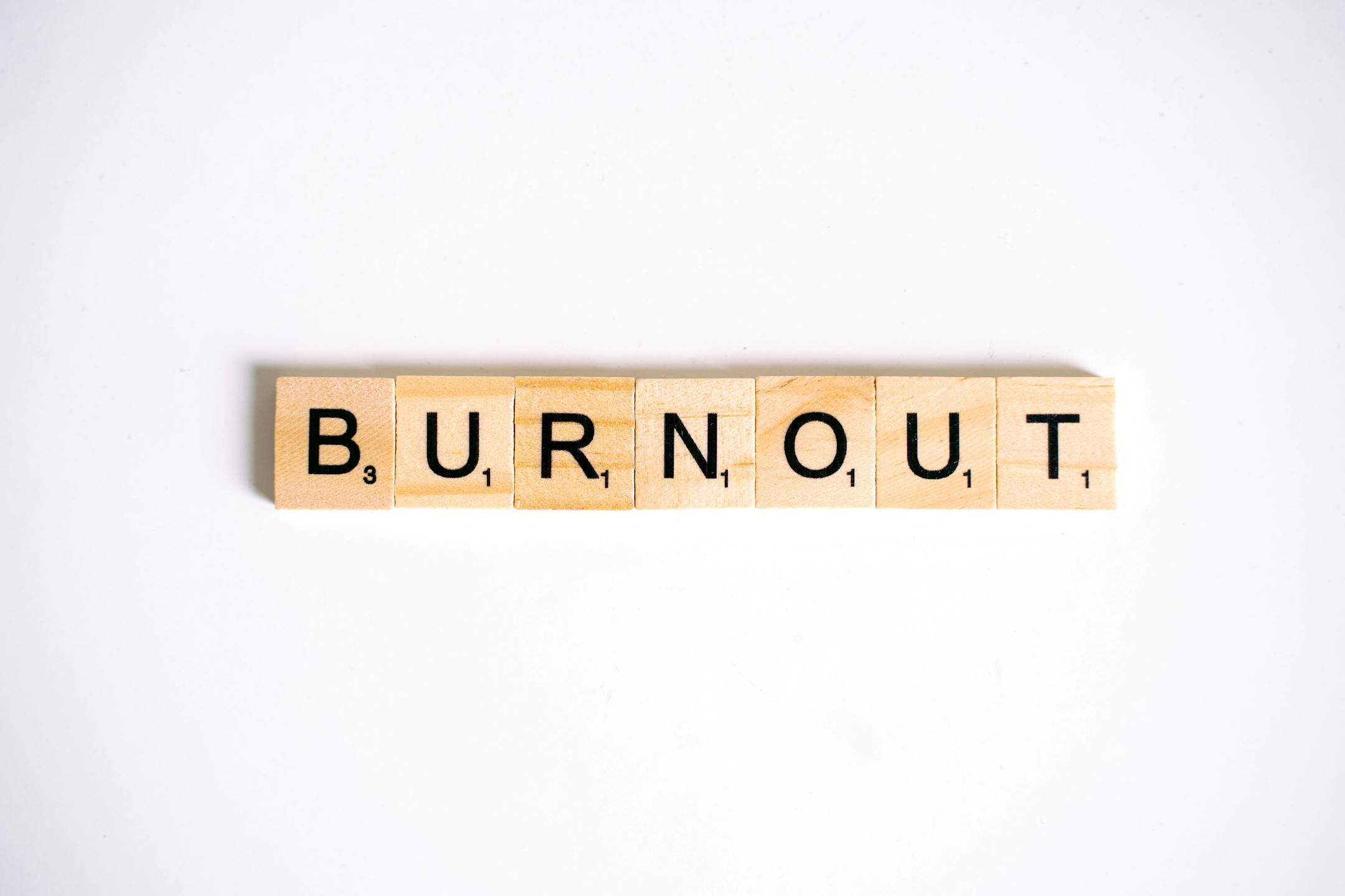 Burnout spelled with Scrabble tiles on a white background, symbolizing stress and recovery at Cognitive Analytica Lebanon.
