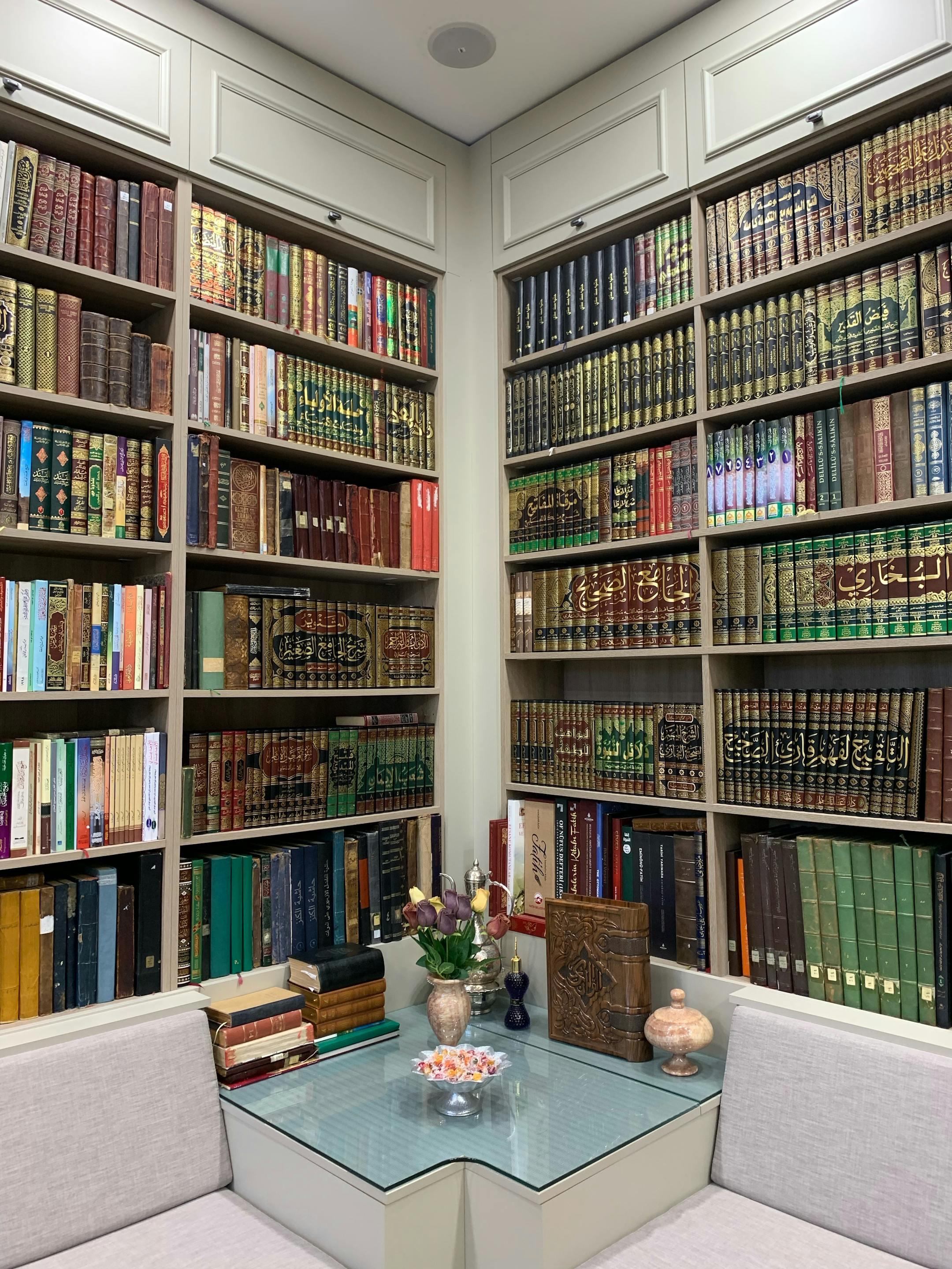A cozy library corner with Arabic books, elegant decor, and comfortable seating.