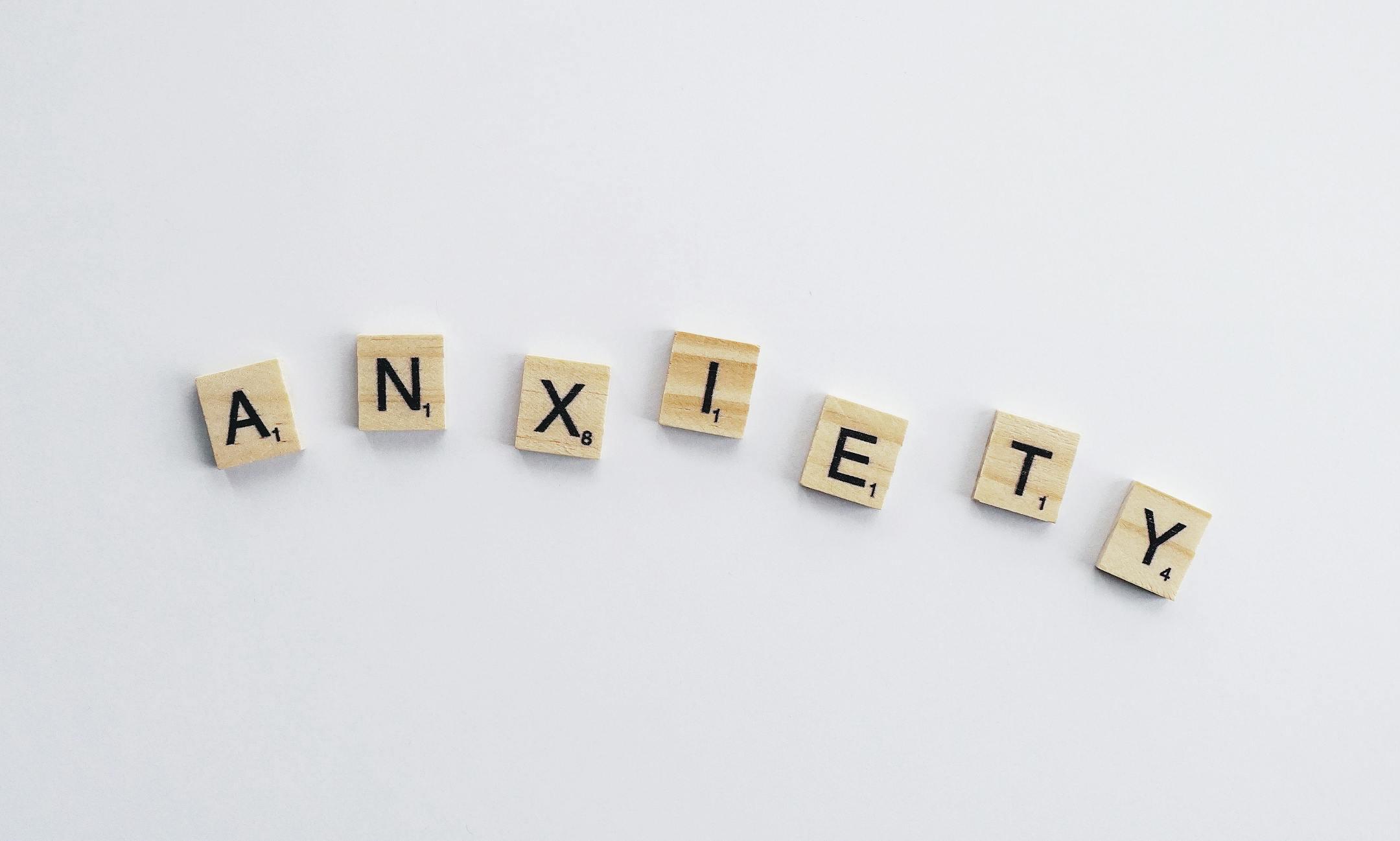 Wooden letter tiles spelling anxiety on a white background, symbolizing mental health awareness and support at Cognitive Analytica in Lebanon