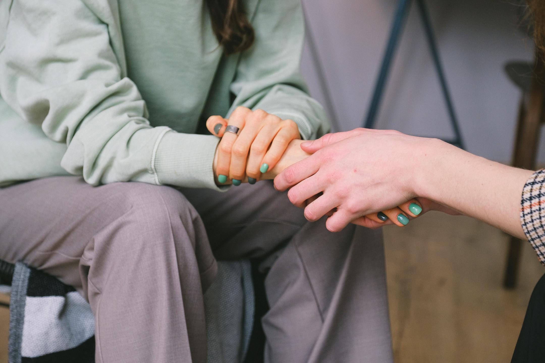 Close-up of a Cognitive Analytica counselor and client holding hands during a comforting counseling session in Lebanon, reflecting empathy and trust.