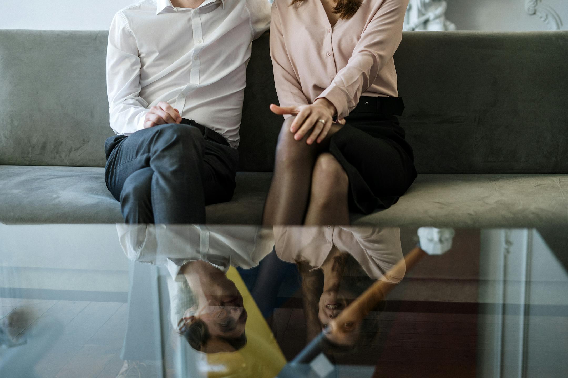 A couple sitting on a sofa, reflected on a glass table during their Cognitive Analytica couples therapy consultation in Lebanon