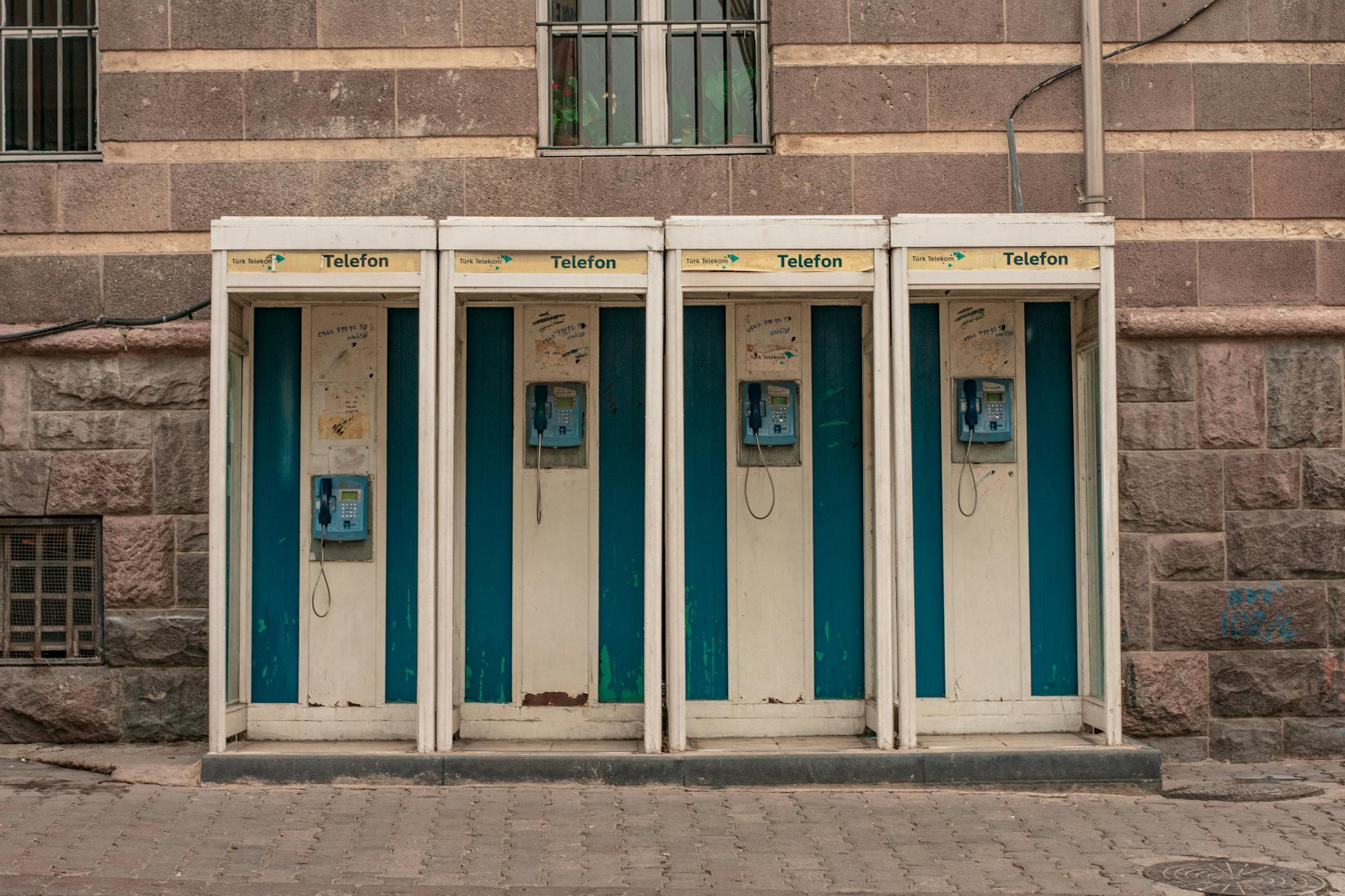 Four vintage phone booths lined up on an Ankara sidewalk, capturing nostalgia.