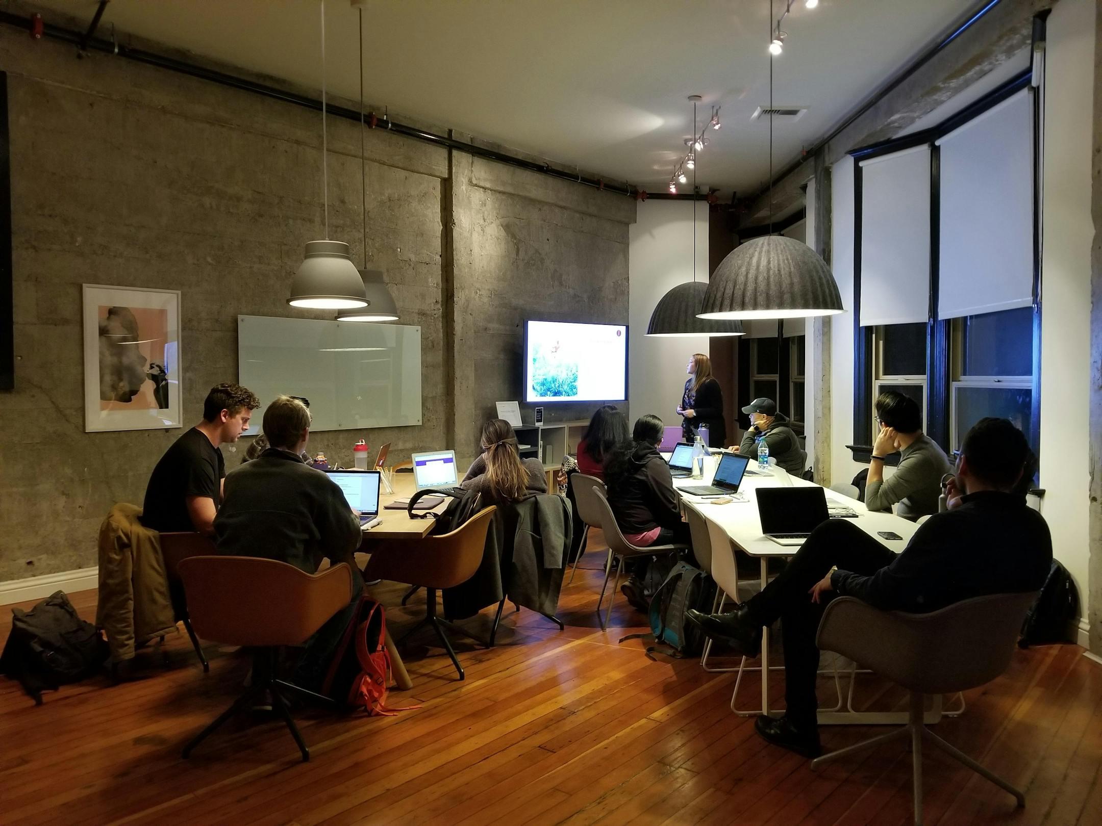 A diverse team collaborating in a modern office with laptops and a presentation screen, representing Cognitive Analytica’s organizational psychology and workplace mental health solutions.