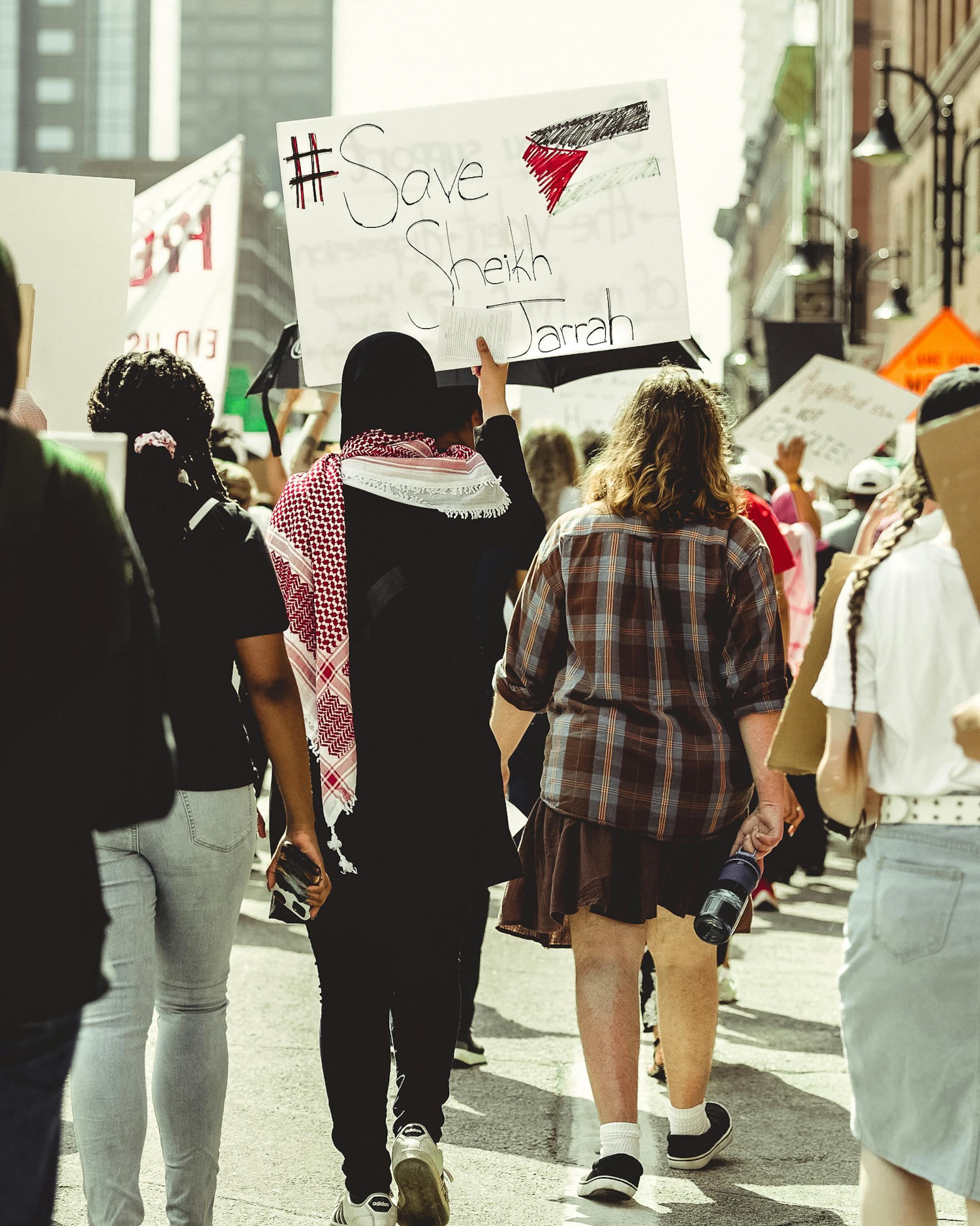 Street protest in Louisville advocating for Sheikh Jarrah with diverse participants holding signs.