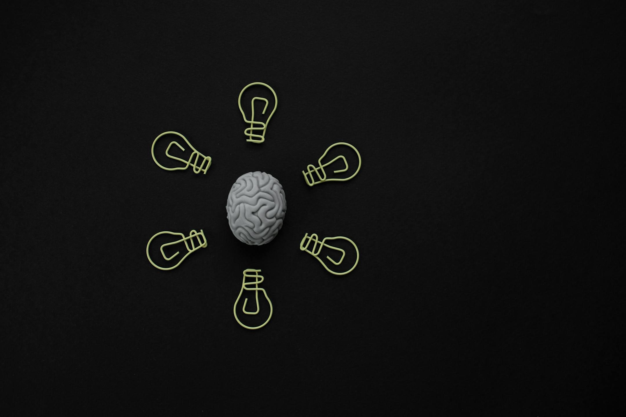 Cognitive Analytica conceptual image showing a brain surrounded by light bulb clips on a black background, symbolizing personal growth, problem-solving, and emotional clarity through therapy in Lebanon.