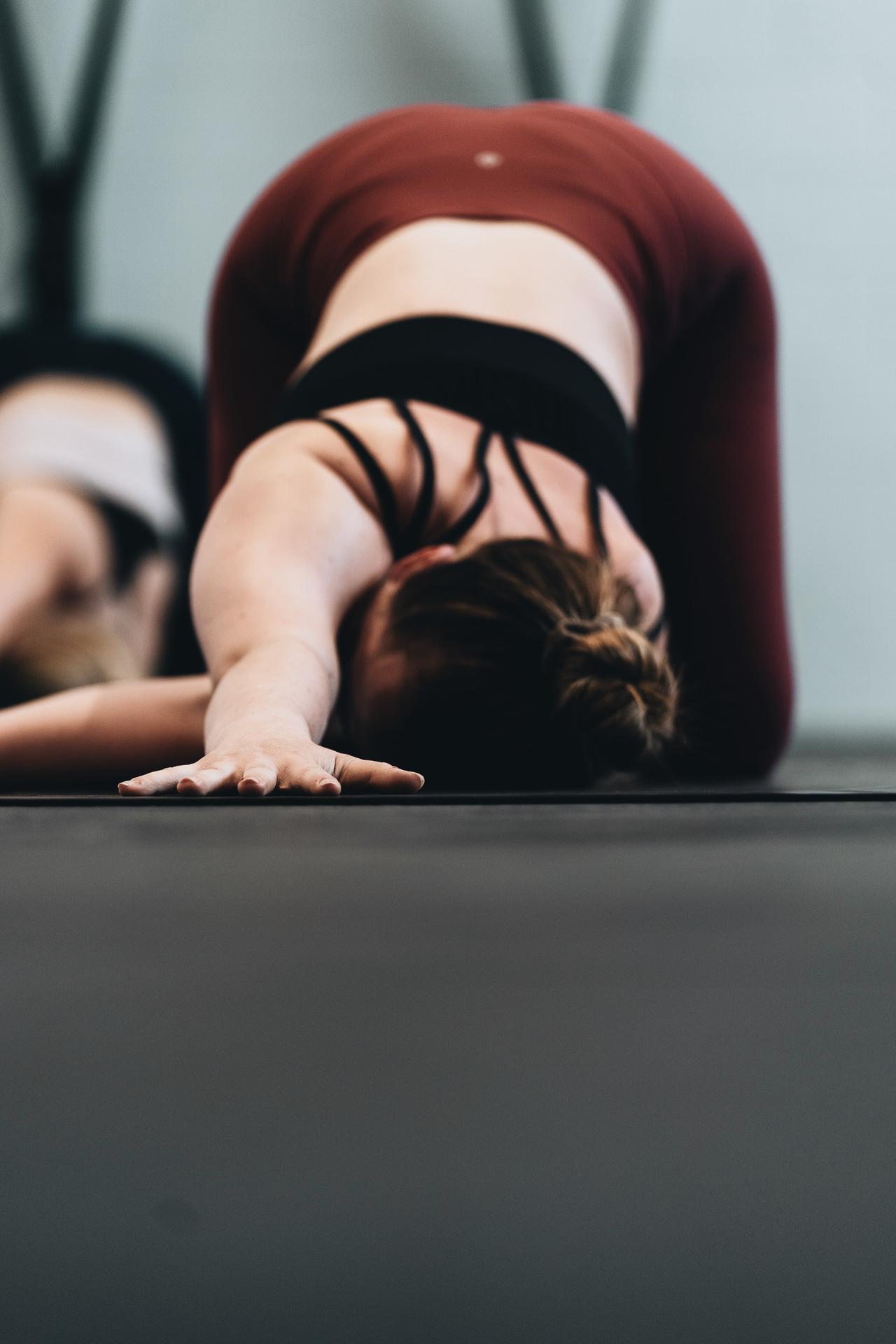 Image of a woman in workout clothes doing a Pilates stretch on the floor.