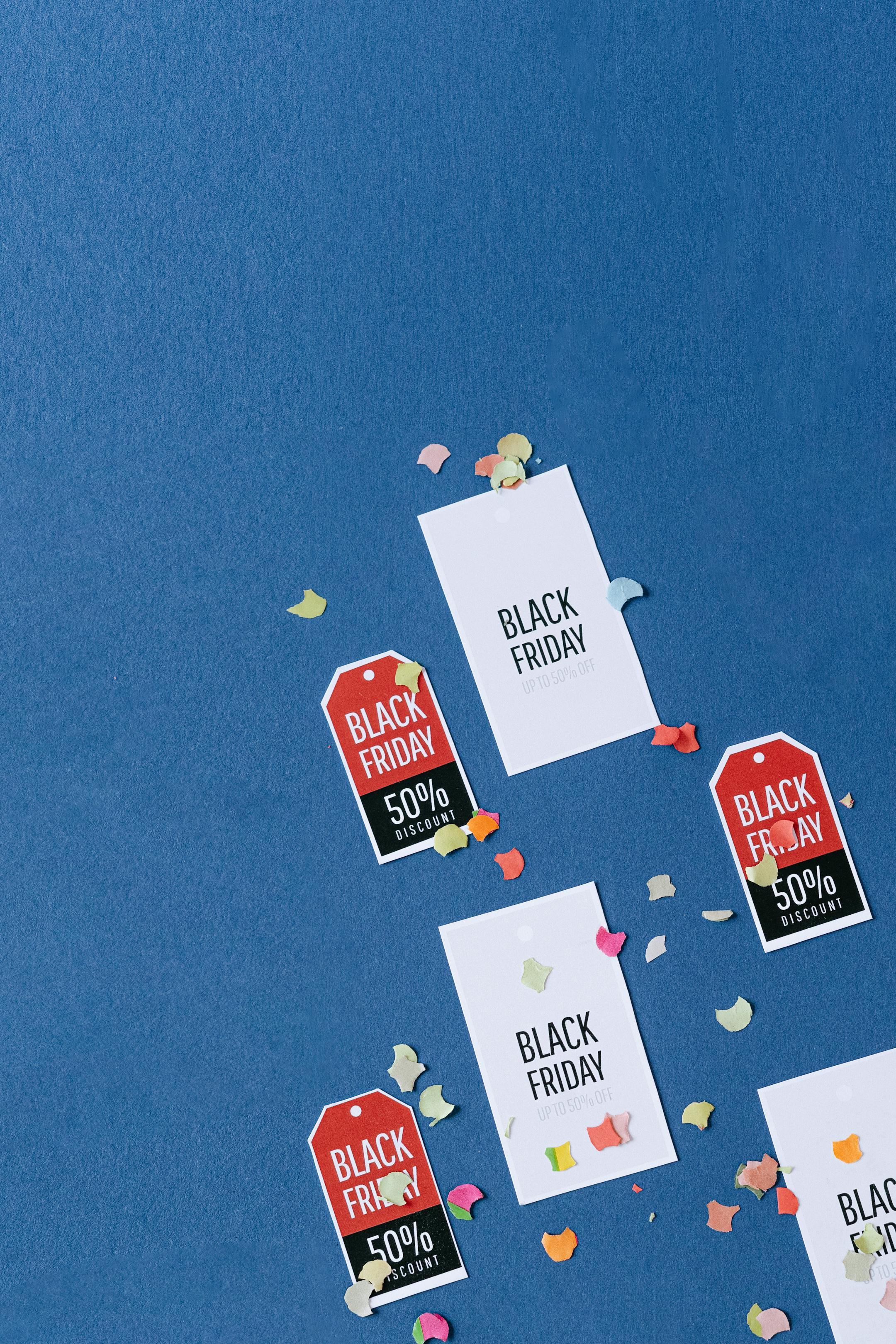 Colorful sale tags and confetti on a textured blue surface for Black Friday deals.