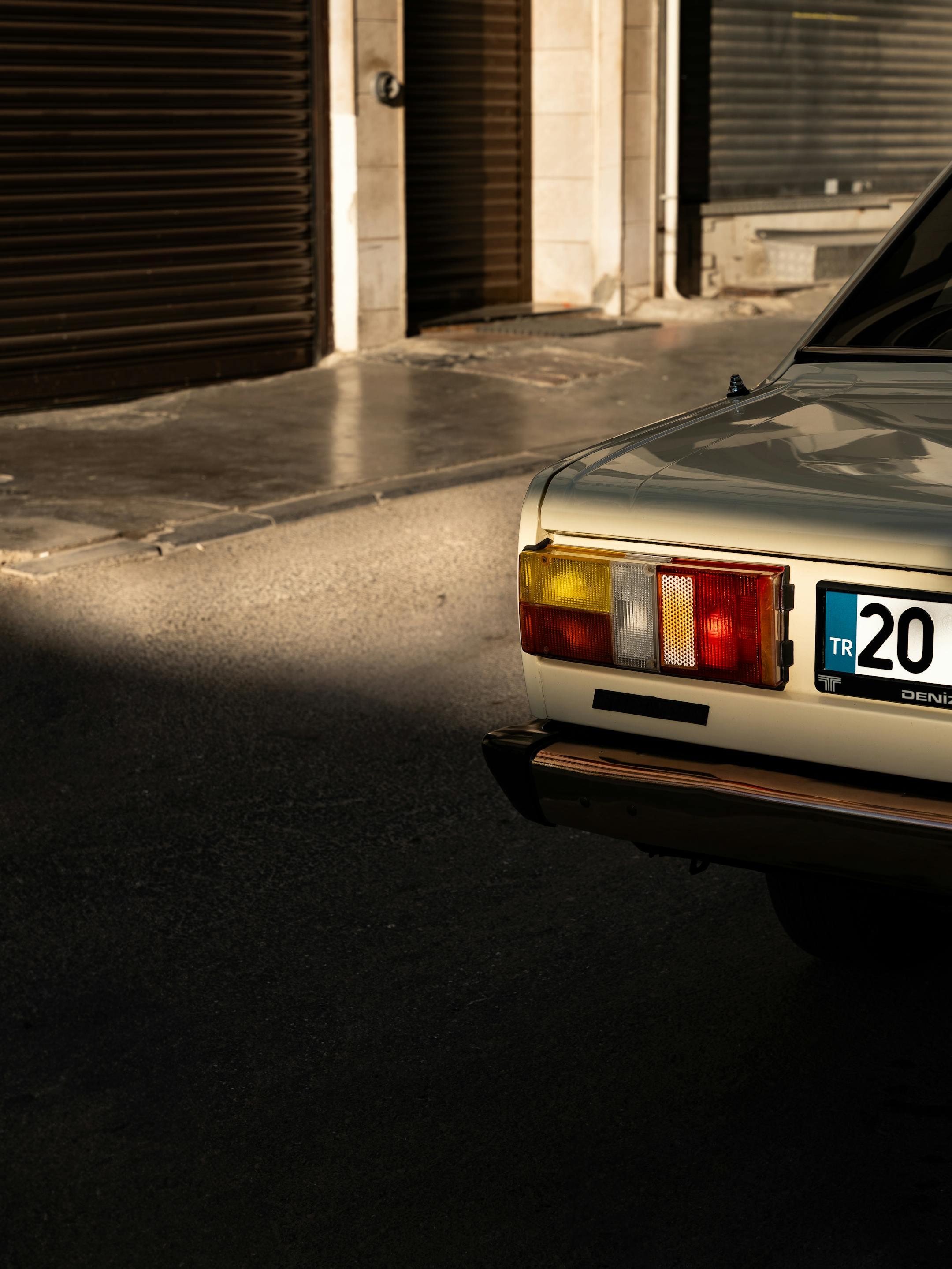 A classic car's tail light in a sunlit urban İzmir street, exuding vintage charm.
