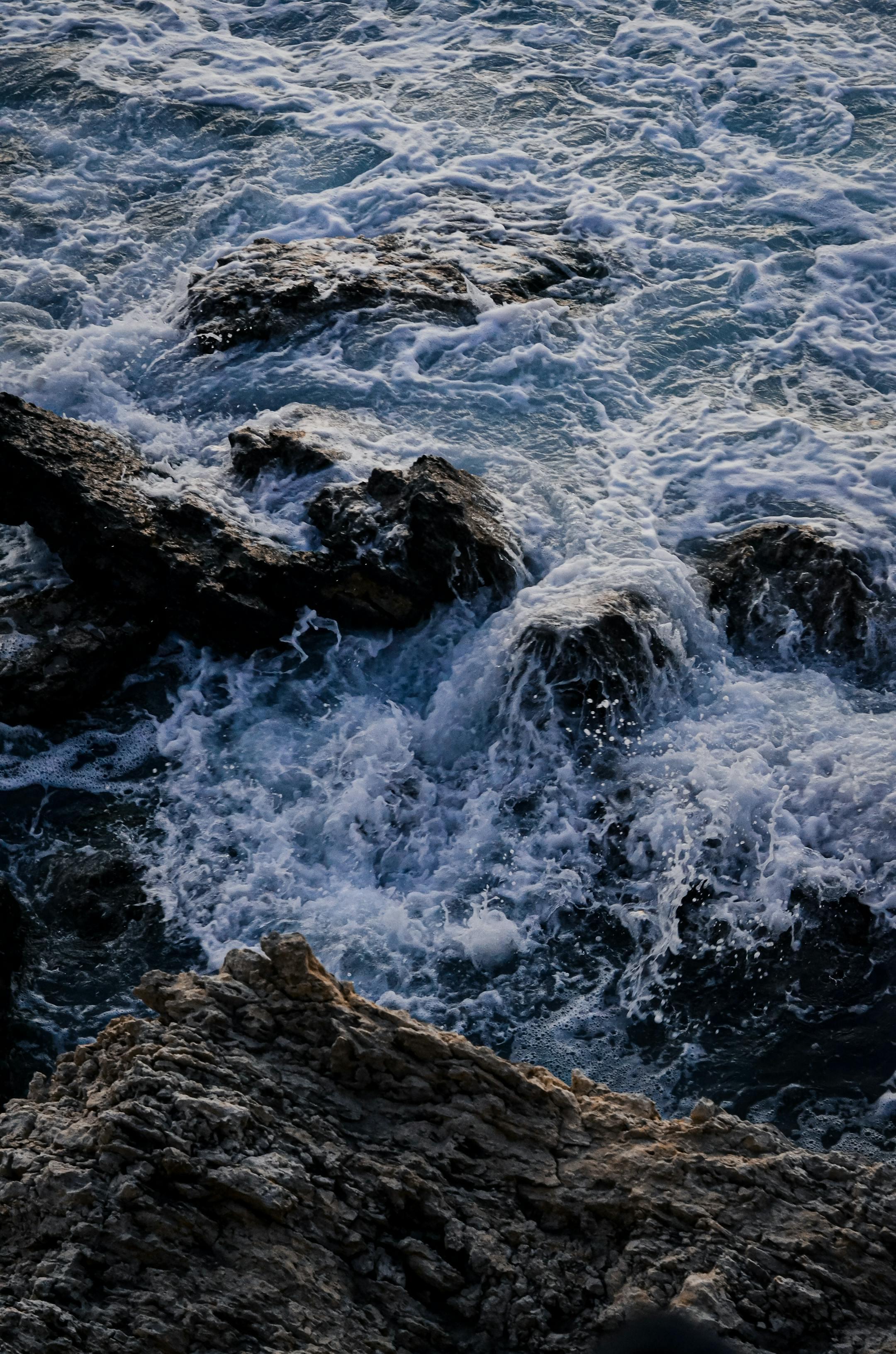 Powerful waves crash on rough rocks, capturing nature's raw energy near the sea.