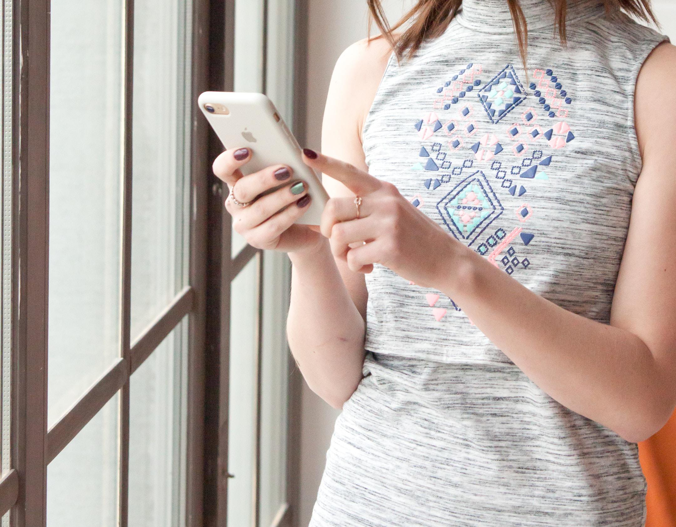 Lady holding the smartphone in front of the window. 
