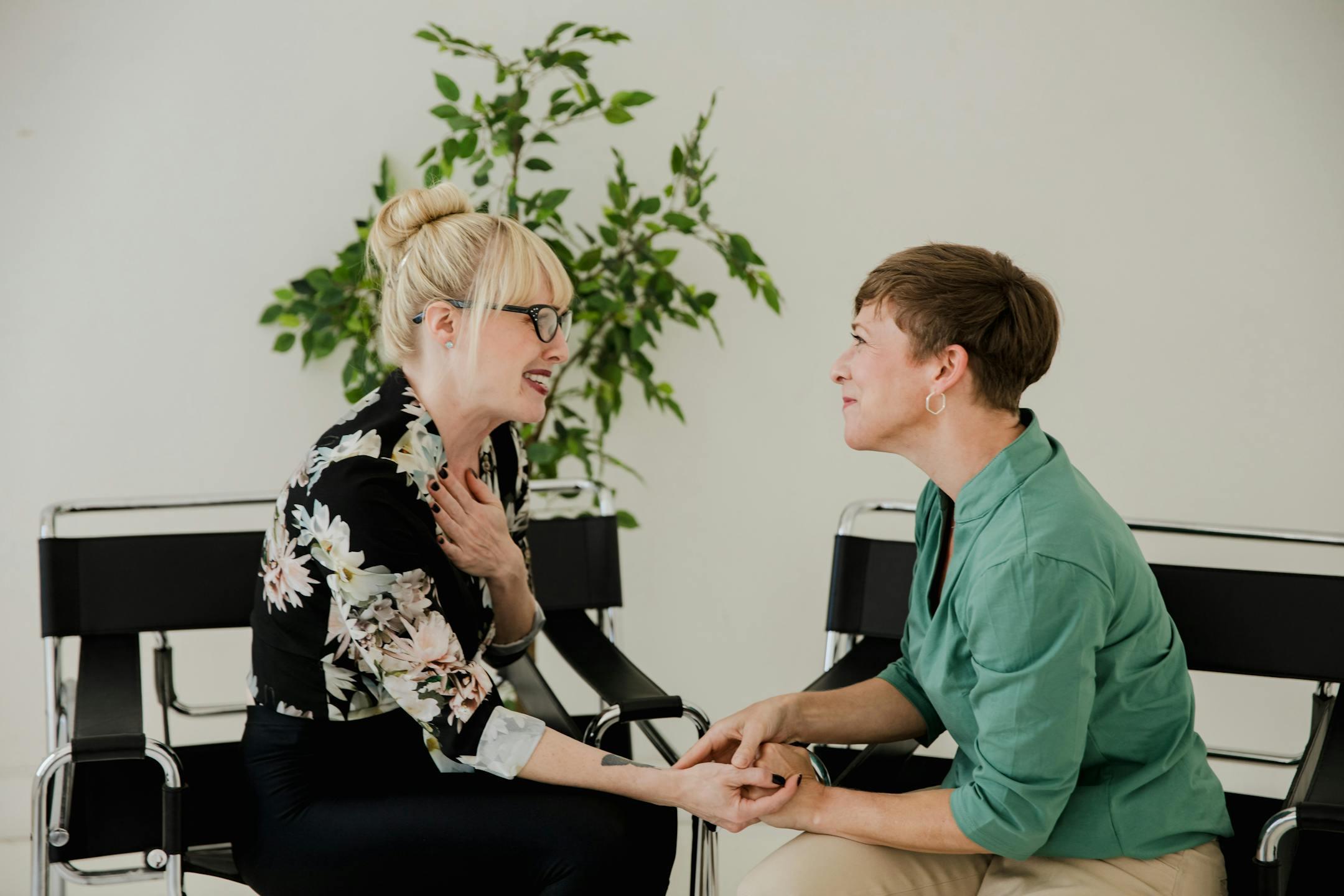 Two women sitting together, sharing a supportive and positive interaction indoors.